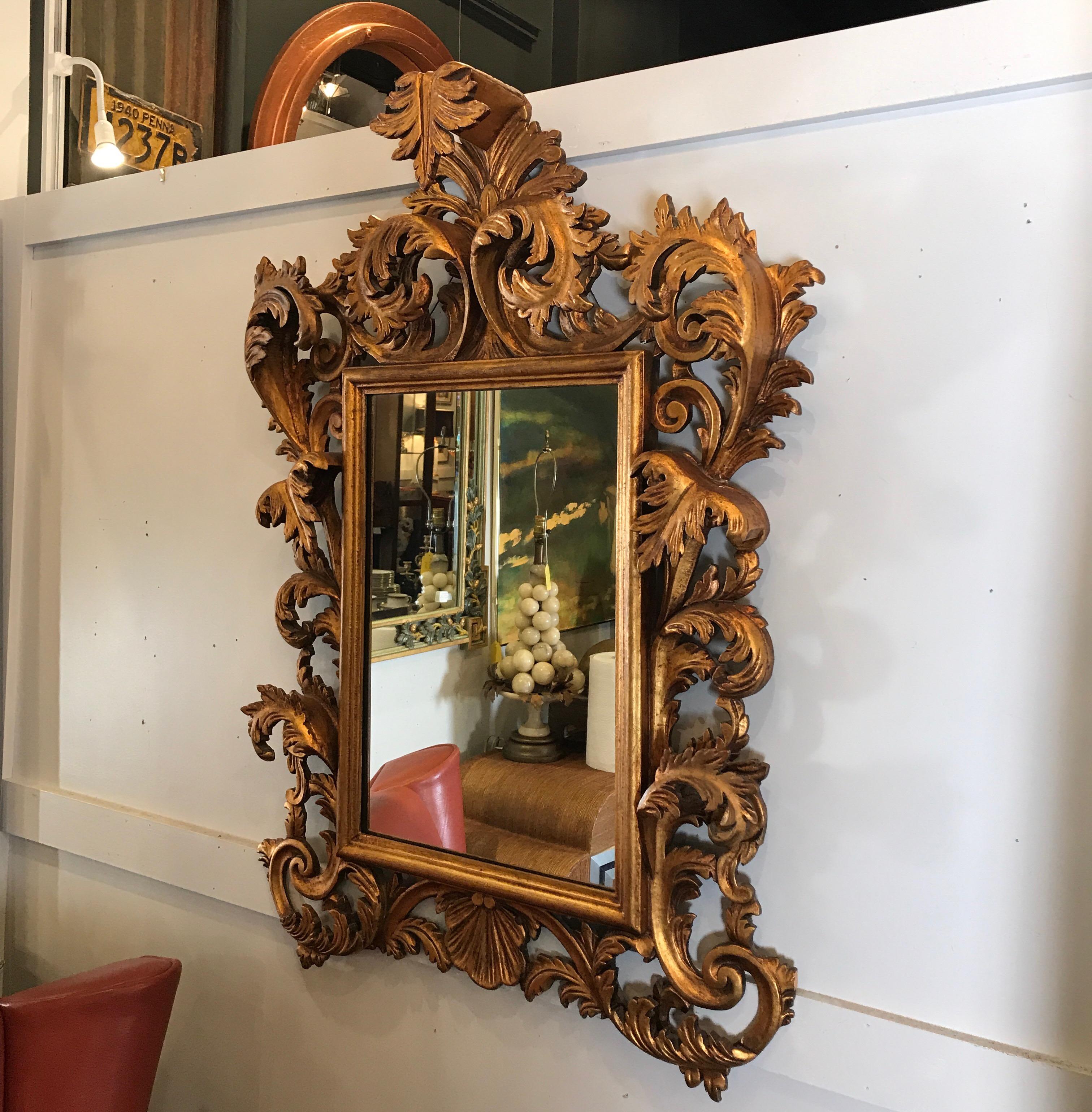 Elaborately carved Italian giltwood Rococo mirror. The frame with high relief scrolls of acanthus leaves at the top, sides and bottom. The top with a center plume pediment.