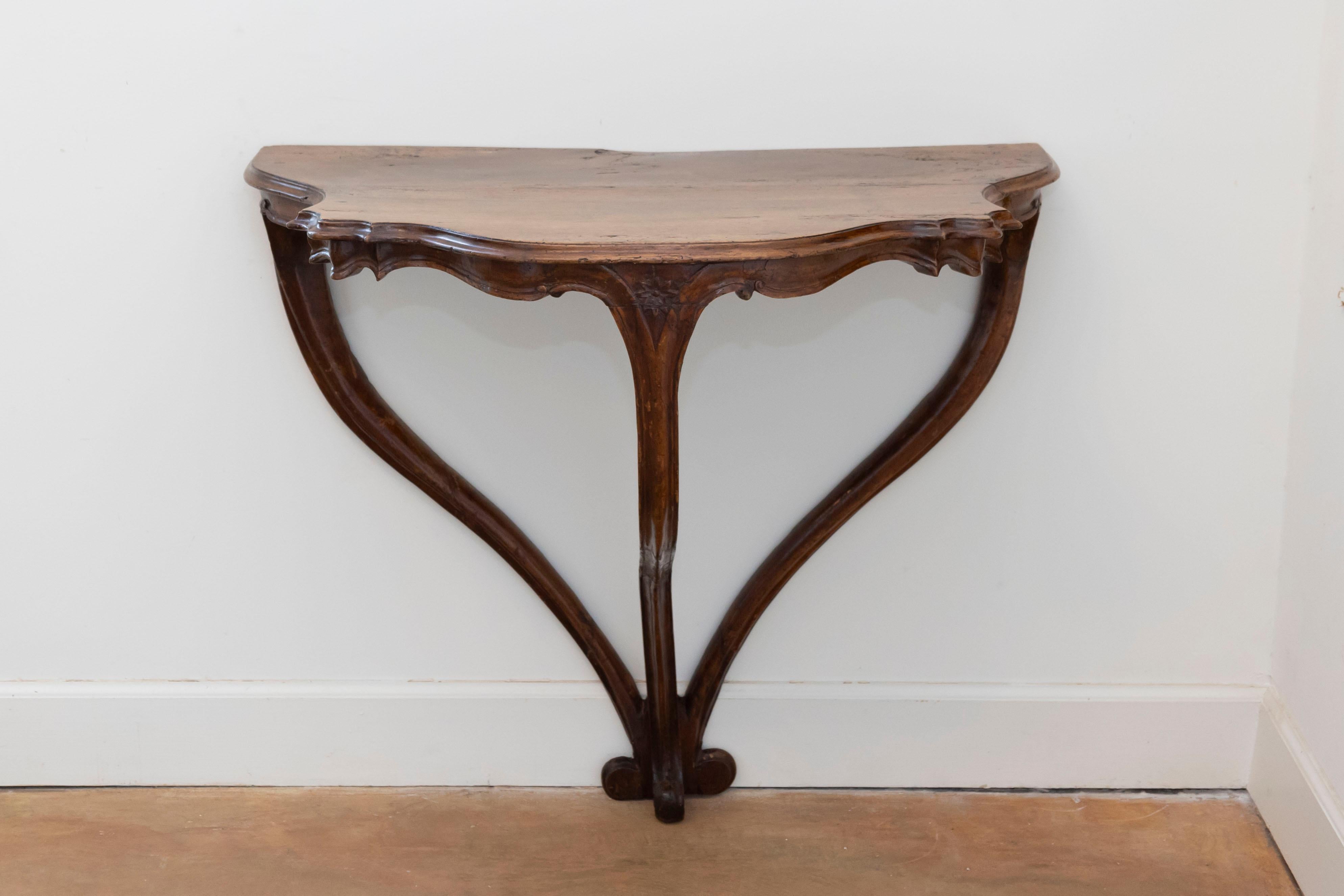 An Italian Rococo period walnut console table from the late 18th century, with cabriole legs, scrolling feet, carved apron and authentic patina. Born in Italy at the end of the 18th century, this walnut console table features a serpentine front top,