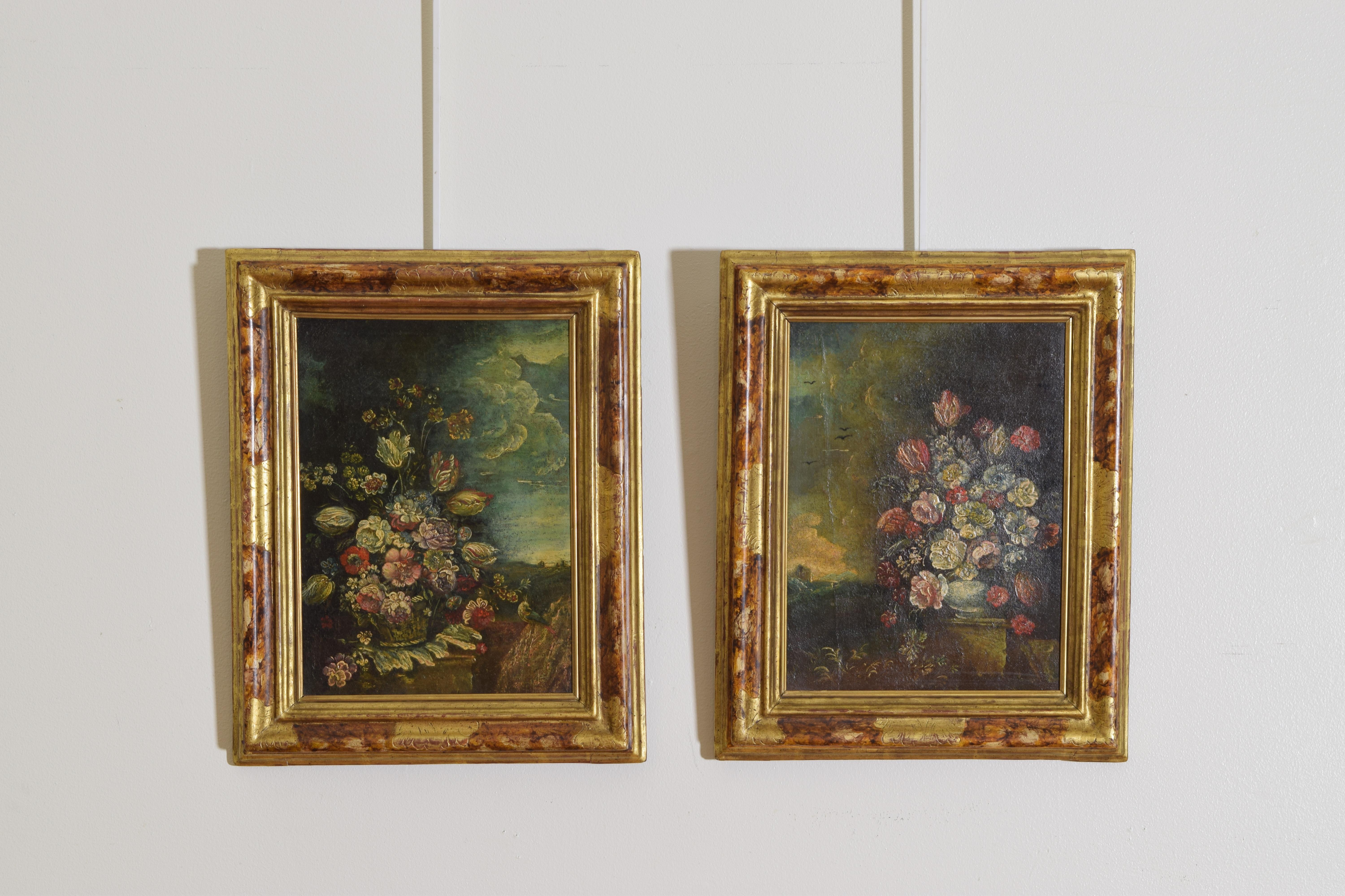 The pair of oils on canvas depicting floral arrangements, one in a basket, the other in a pot, both on plinths, each with dwellings and mountains in the distance, one with a bird in the foreground, the other with birds in the air, both with cloud