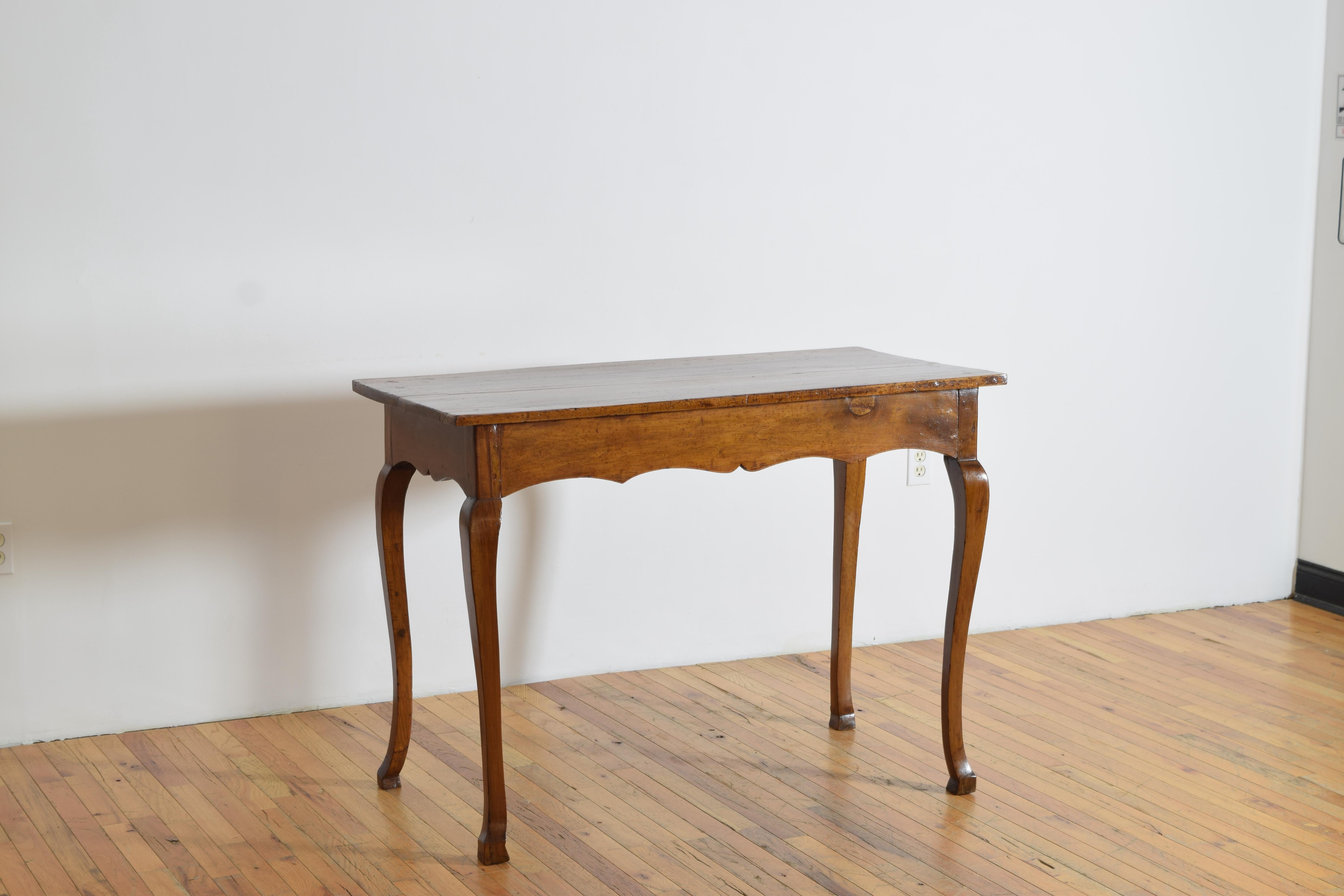 likely of Tuscany origin, constructed entirely of solid walnut, having a rectangular top above a shaped apron on all sides, raised on slightly flared cabriole legs terminating in shaped feet