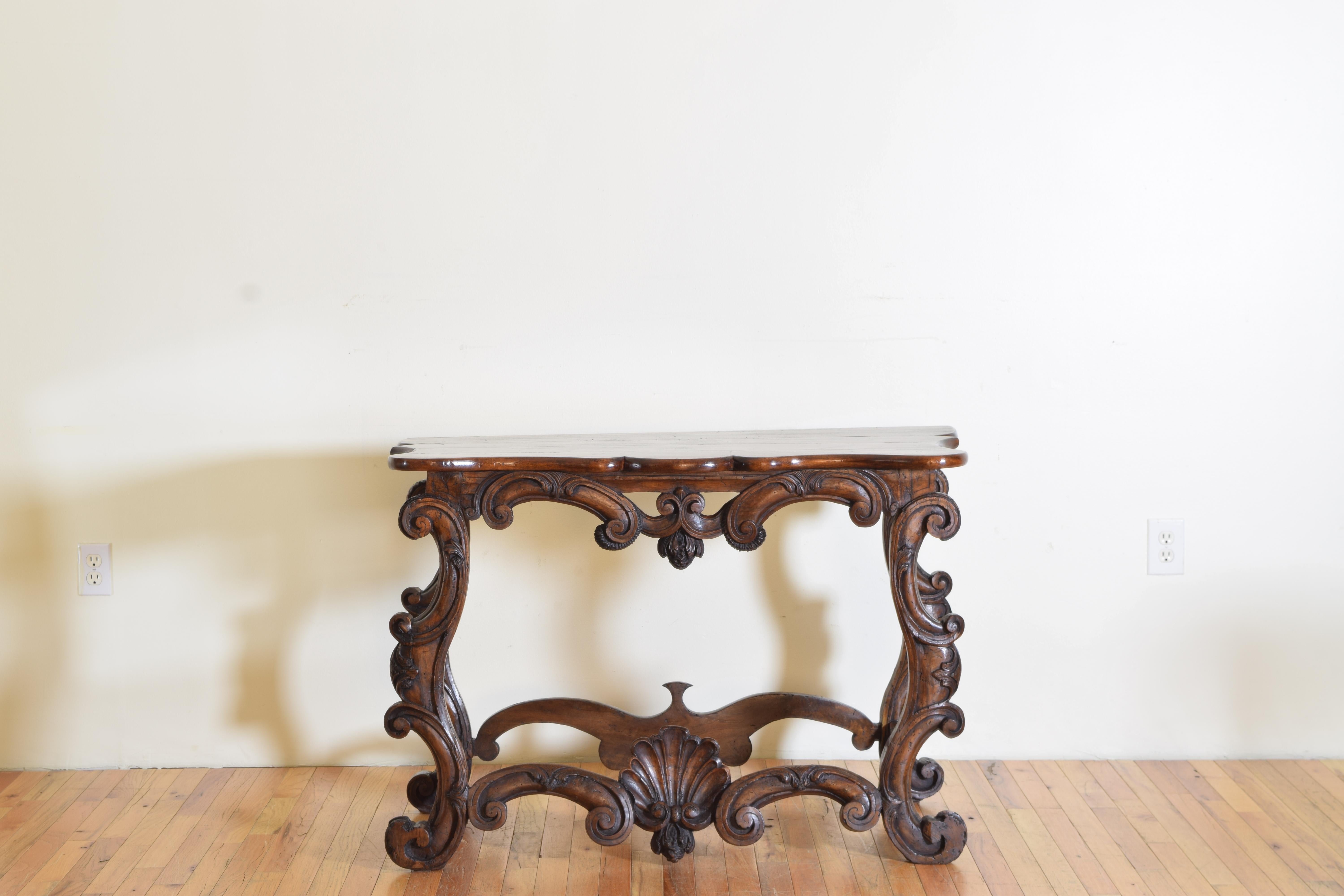 Having a later walnut top with curved sides and a serpentine shaped front above a conforming frame carved from pinewood comprised of c-scrolls and centering a large carved shell.