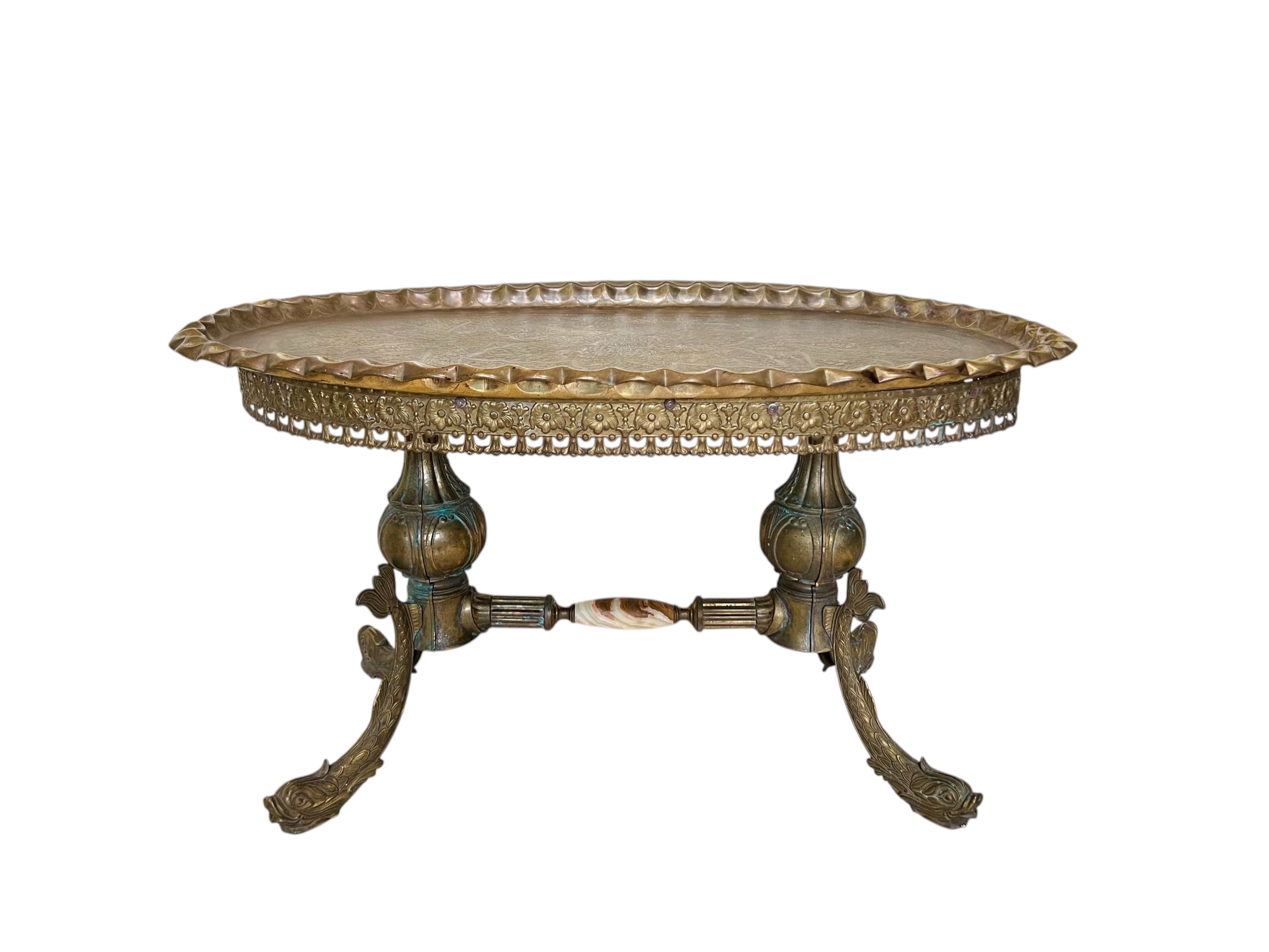 A mid-century Italian rococo revival oval brass cocktail table with removable tray top. This richly decorated piece features a double pedestal base connected by a fluted stretcher with an onyx center piece, a pierced brass gallery apron, and koi