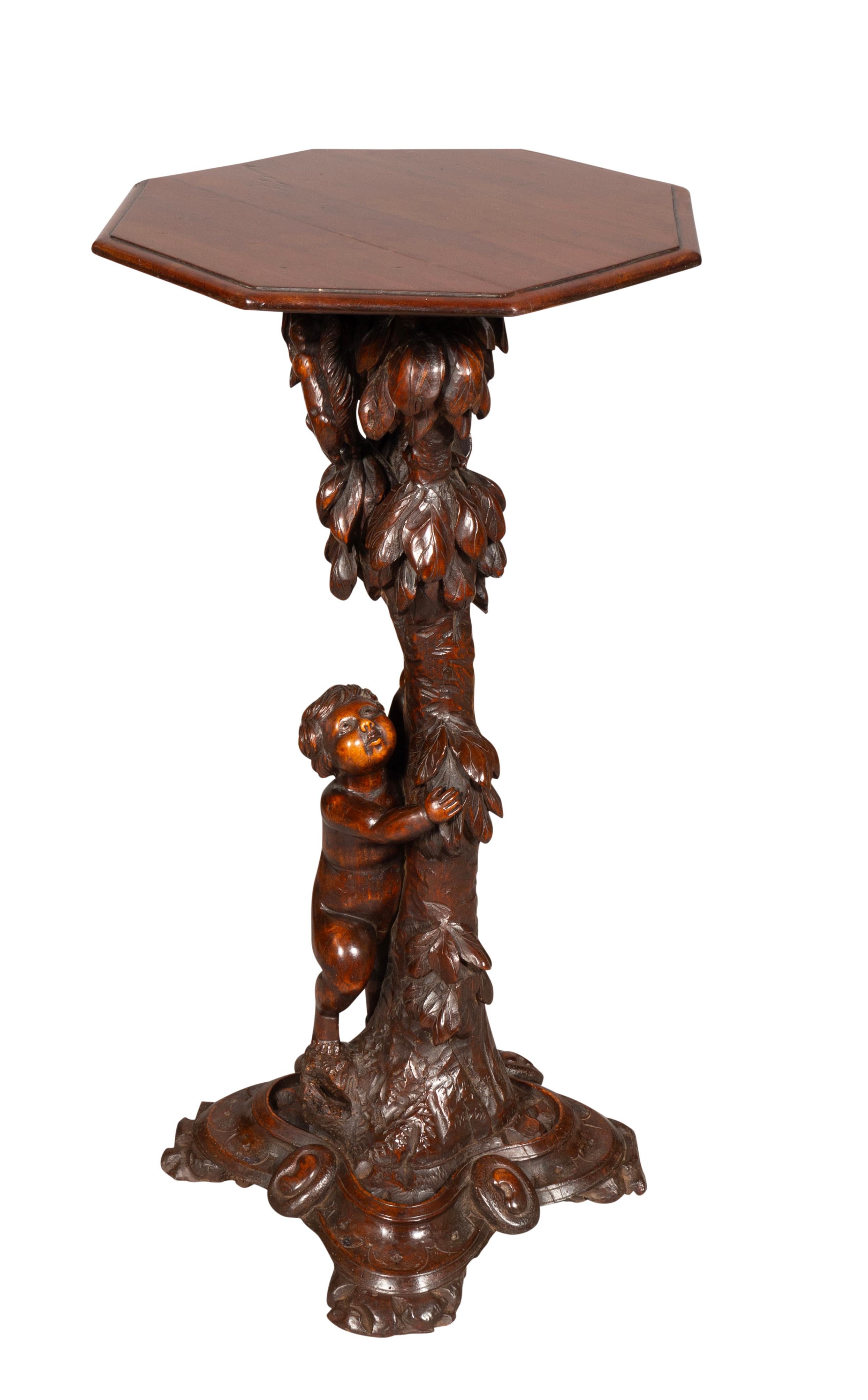 With octagonal top with support carved as a tree with cherub. Shaped carved base.