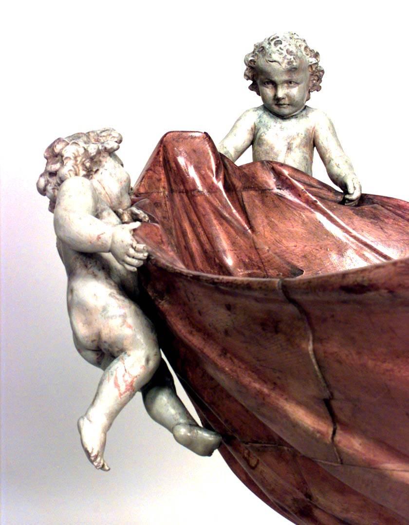 Italienische Rokoko-Krippe (18/19. Jh.) mit geschnitztem Amor auf rustikalem geschnitztem Holzsockel.
