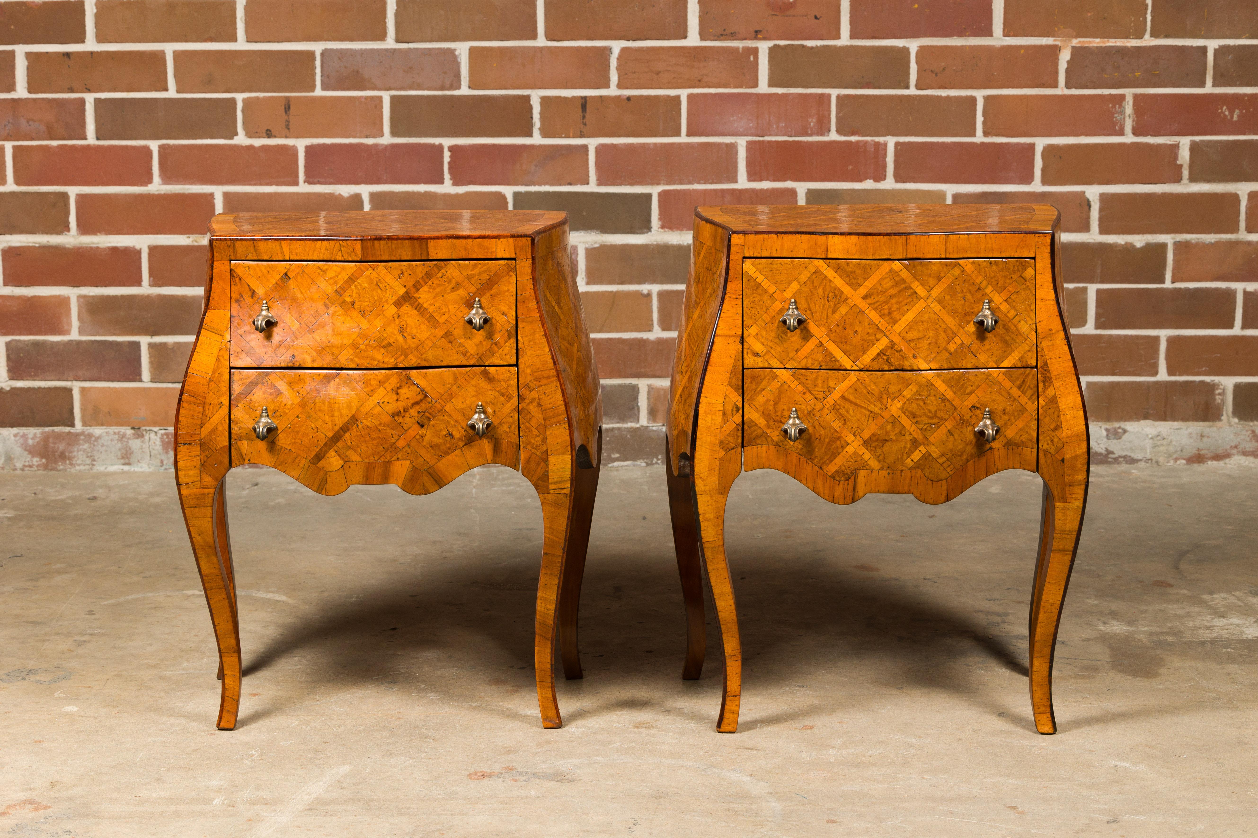 A pair of Italian Rococo style burl wood bedside chests from the Midcentury period, with two drawers, marquetry décor, serpentine front and cabriole legs. Indulge in the ornate charm and exquisite craftsmanship of these Italian Rococo style burl
