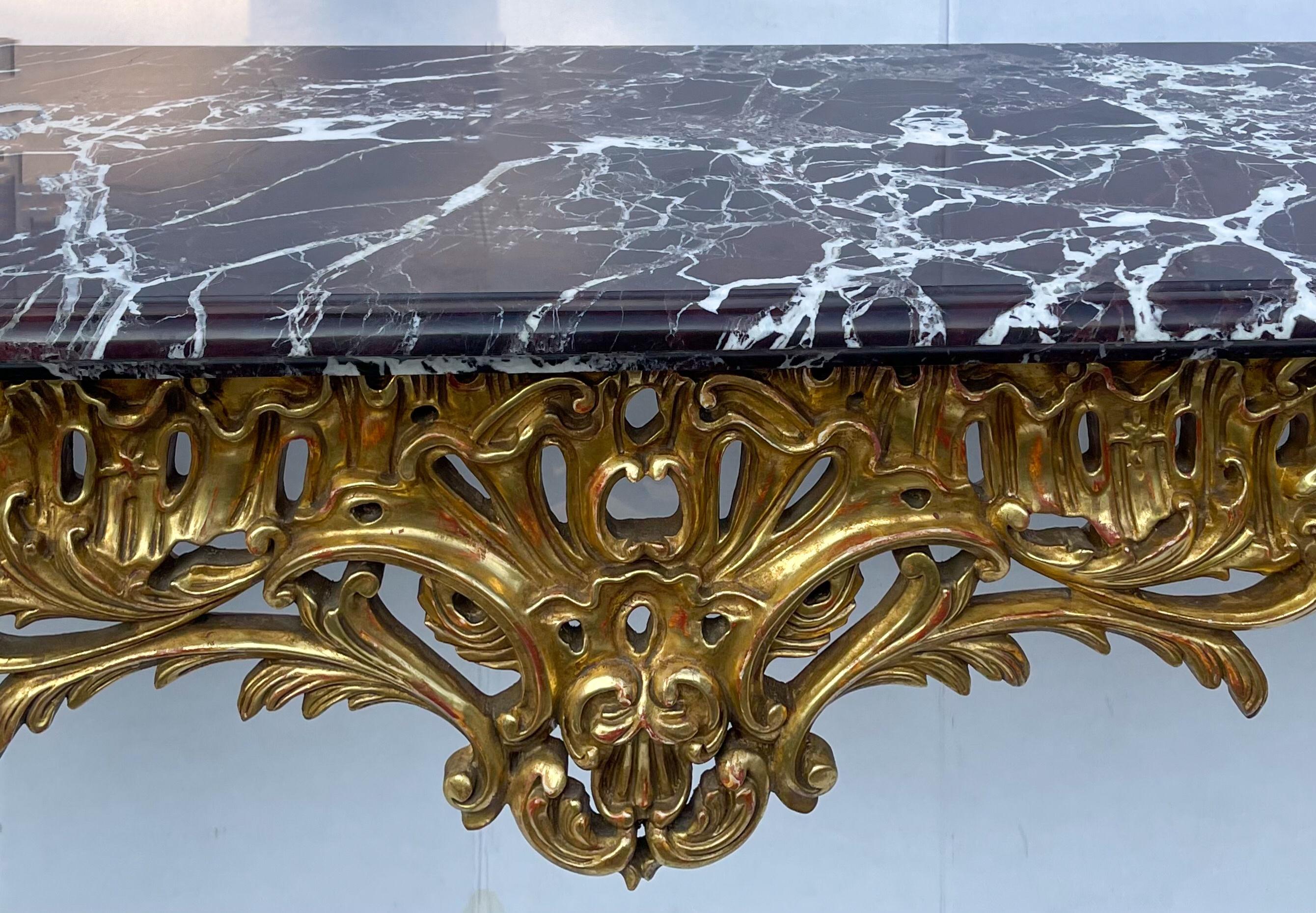 Dieser Konsolentisch ist eine Reproduktion einer französischen Antiquität aus der Mitte des 18. Jahrhunderts. Die Wasservergoldung ist außergewöhnlich, der rougefarbene Marmor hat weiße Äderungen und einige größere, fast schwarze Stellen. Die Kanten