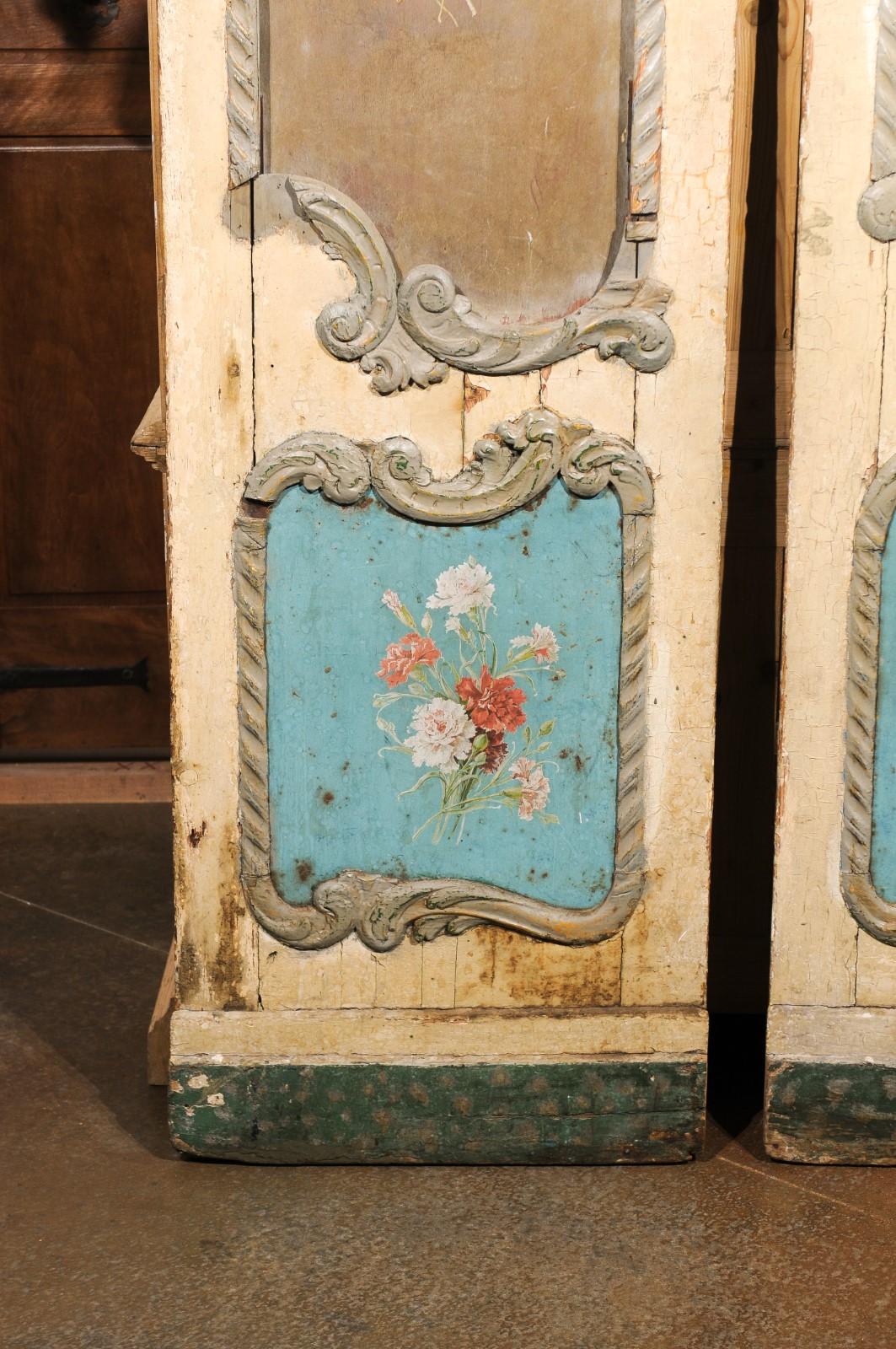 A pair of Italian Rococo style painted wood door panels from the early 19th century, with carved scrolling cartouches, painted bouquets and nicely weathered patina. How not to be immediately charmed by this pair of Rococo style Italian door panels?
