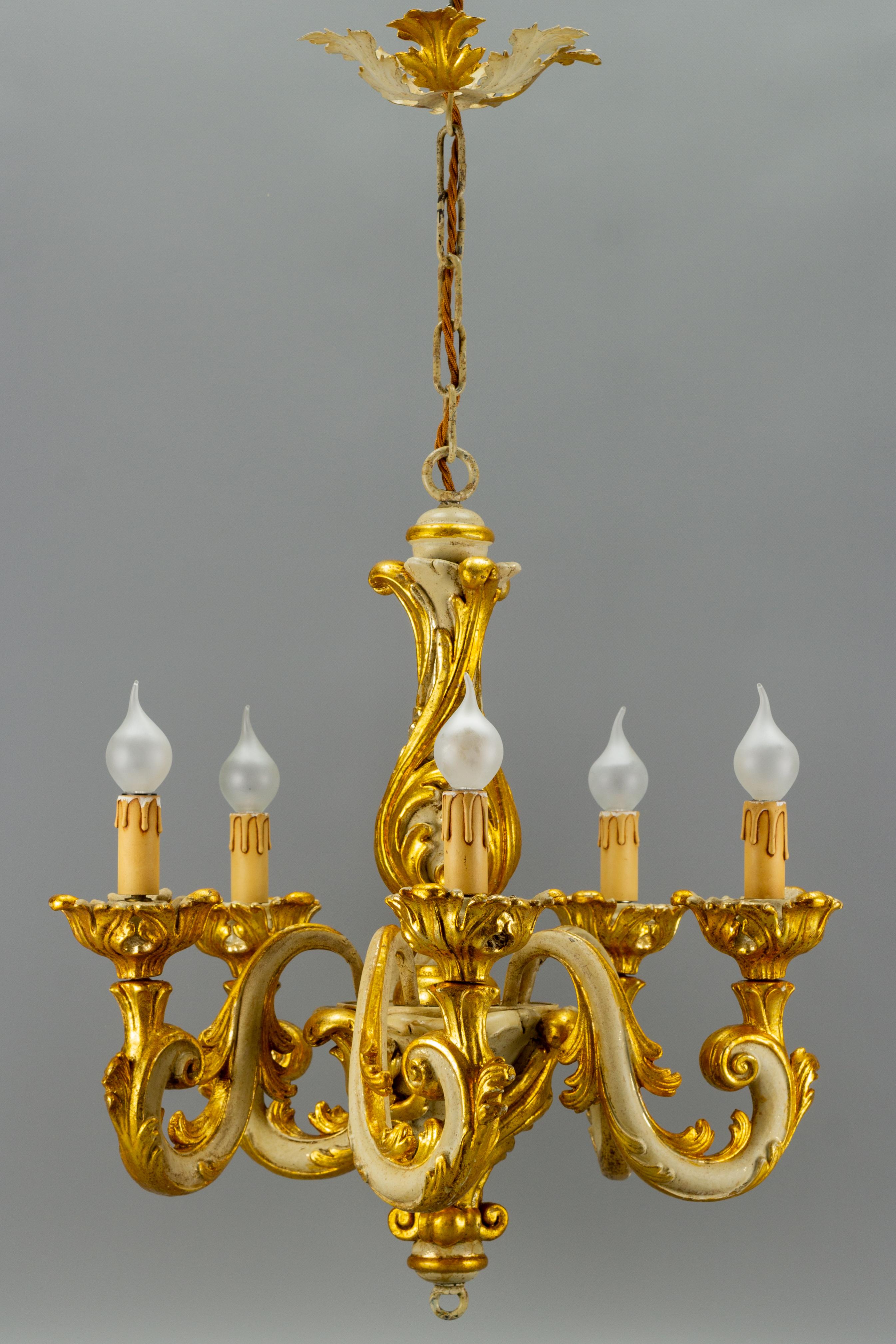 Beautiful Italian vintage chandelier in Rococo style, made of wood and metal. Painted in golden and grey, richly decorated with acanthus leaves motifs. Five arms, each with a socket for E14 size light bulb.
Dimensions: height: 85 cm / 33.46 in;