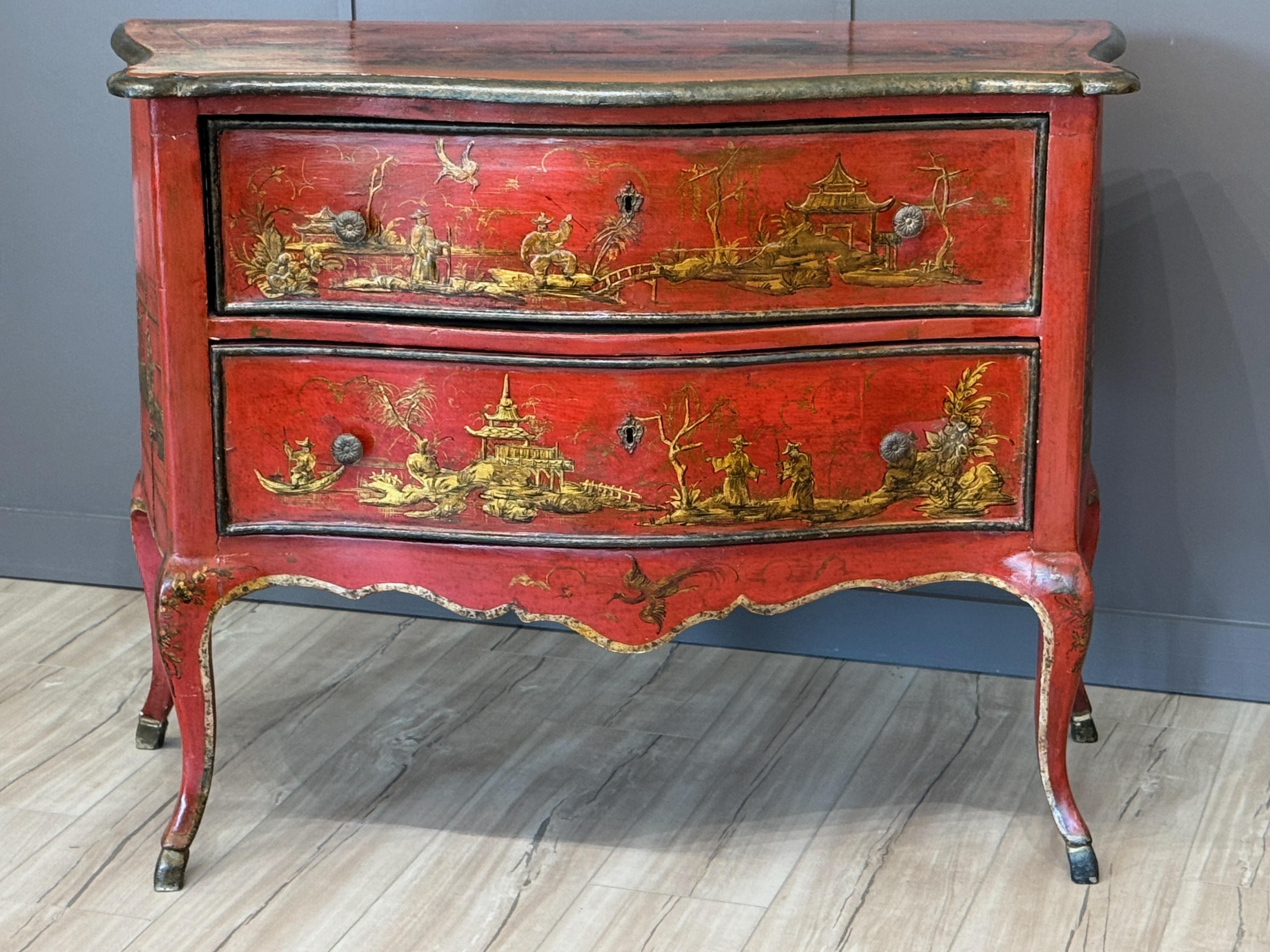 La vibrante lacca scarlatta e le scene di cineserie definiscono questa commode italiana in stile Rococò. Il frontale a serpentina e le gambe cabriole sottolineano la forma aggraziata, mentre le decorazioni dorate aggiungono consistenza e contrasto.