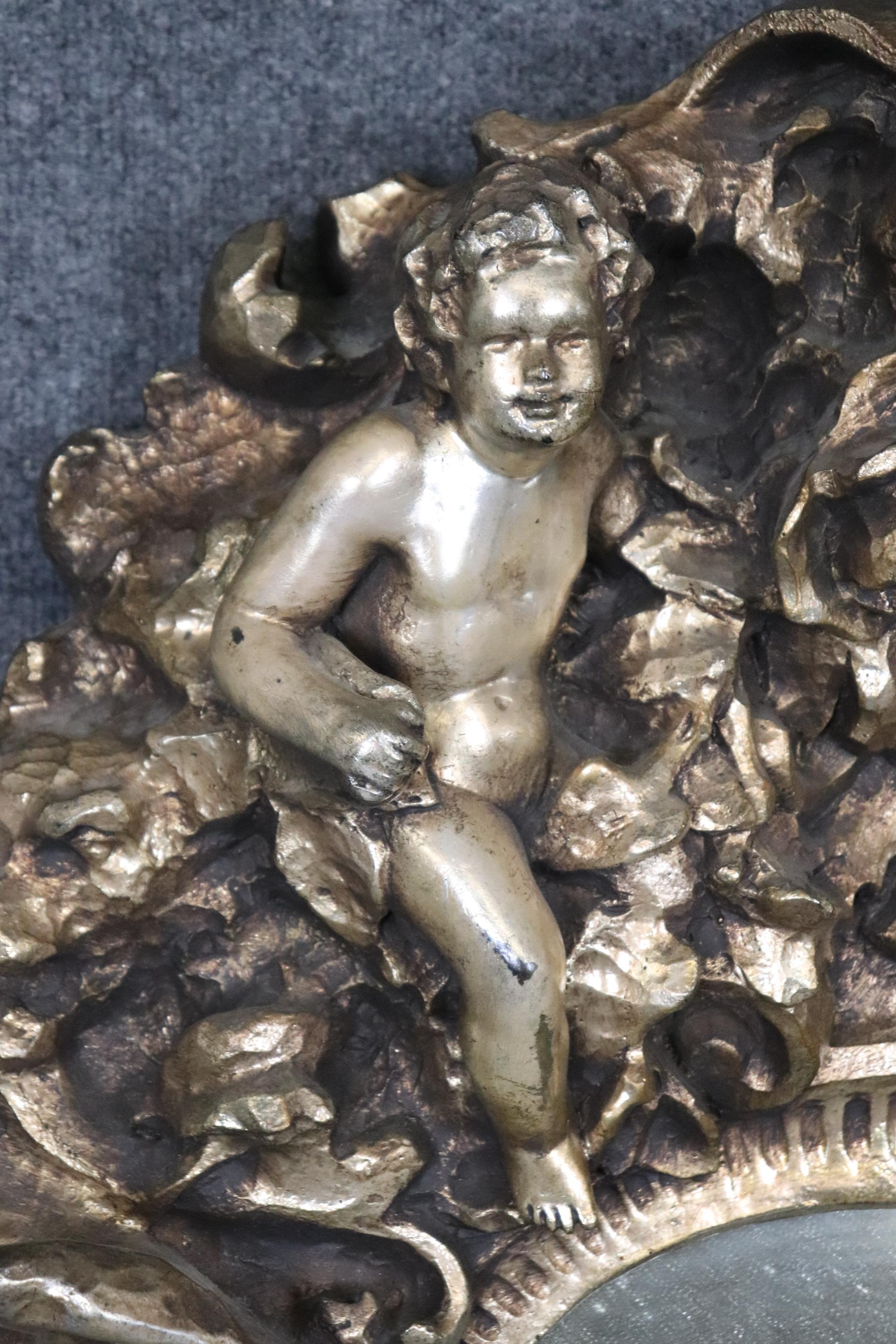 Dies ist ein wunderschöner Spiegel. Der Spiegel zeigt Figuren von Satyrn, Putten und Putten und ist in höchstem Relief mit prächtigem metallischem Blattsilber geschnitzt. Die Figuren sind sehr naturalistisch und das Stück stammt aus den 1950er