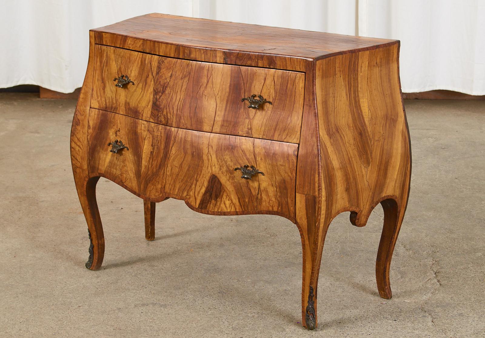 Dramatic Italian bombe commode, chest of drawers, or dresser featuring a patchwork of stunning walnut veneer. Made in the grand Rococo taste the case has elegant and graceful curves with serpentine aprons and cabriole legs. Fronted by two large