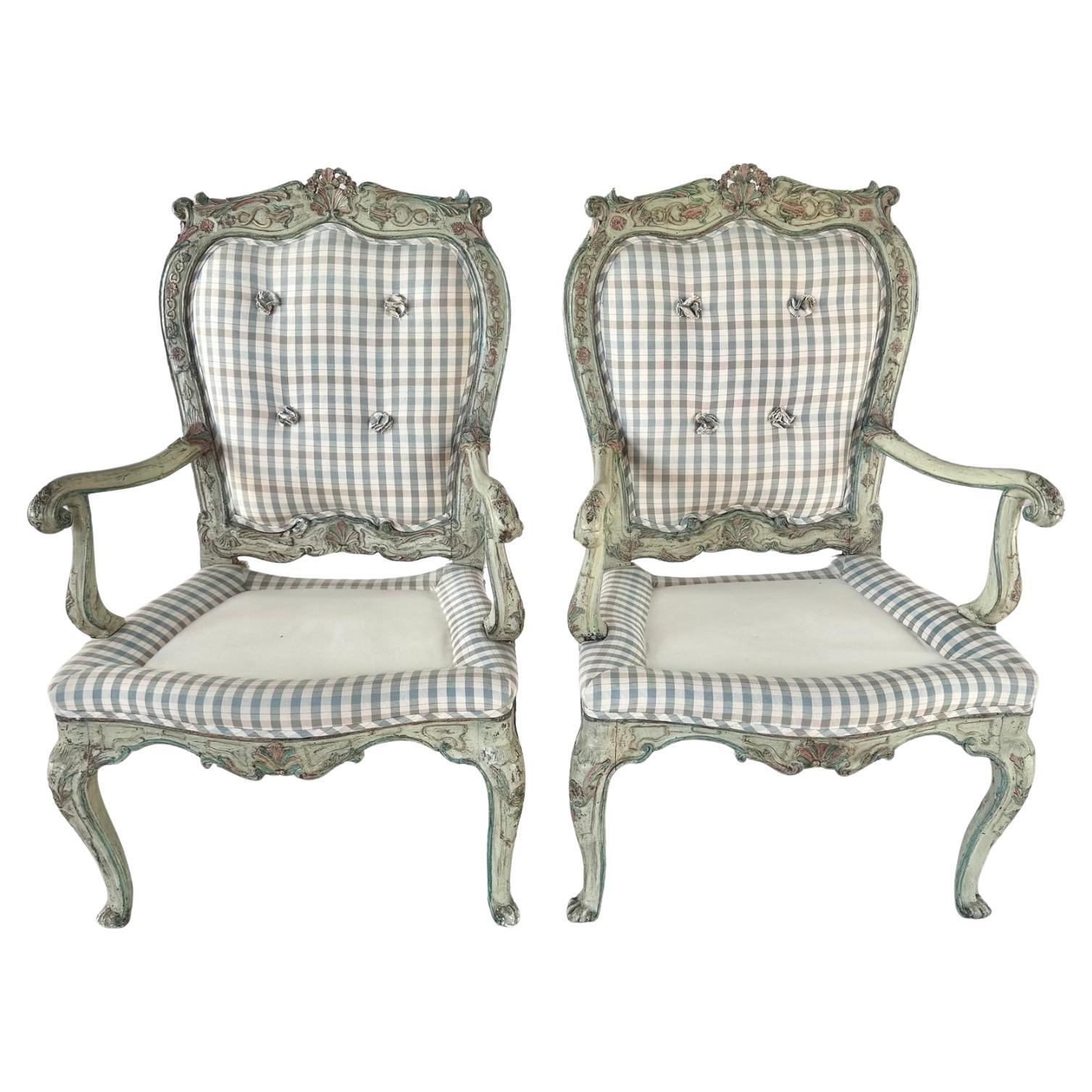 Pareja de sillones rococó italianos del siglo XVIII. Cada silla está tallada y policromada en suaves verdes, rosas y azules, con delicados detalles florales. Los marcos presentan las graciosas curvas y las ornamentadas volutas características del