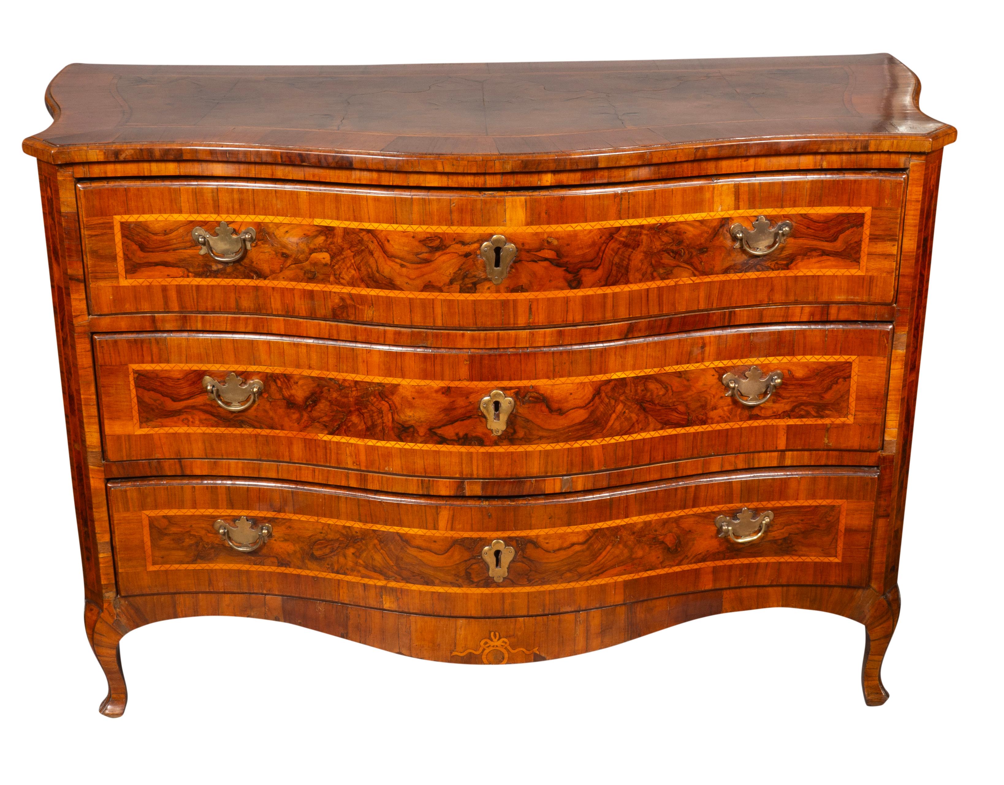 A good clean chest with a serpentine top with banded edge over three conforming drawers with brass handles and escutcheons. Nice brown patina.  Cabriole legs.