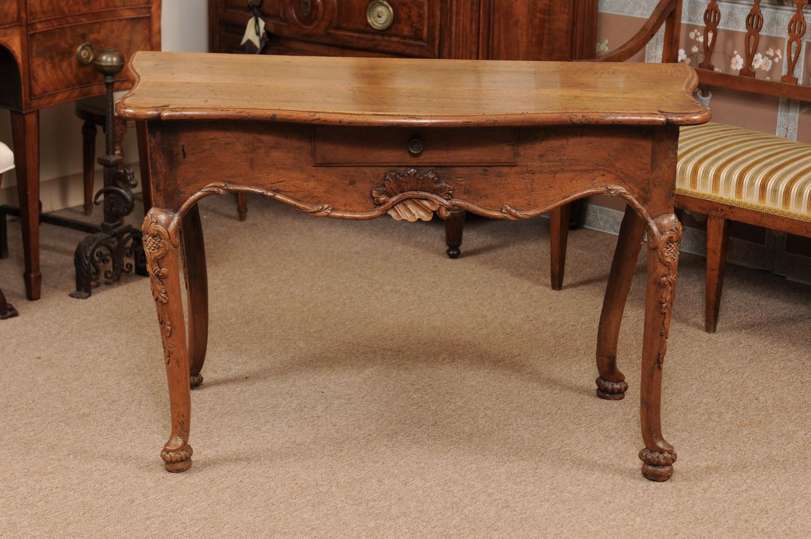 Early 18th century Italian Rococo console table in walnut with serpentine form top, drawer below and carved apron terminating on cabriole legs and pad feet.