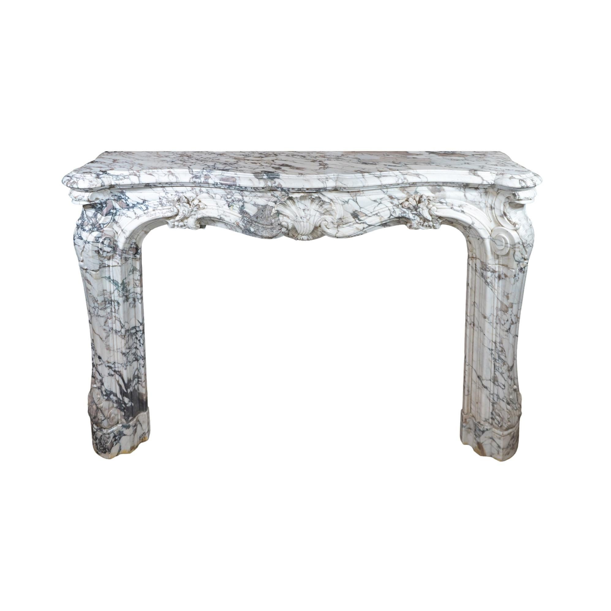 Fabriquée en luxueux marbre blanc Breccia Roman Baixas, cette cheminée en marbre italien présente des détails de sculpture complexes datant du 19e siècle et un motif de coquillage frappant en son centre. Importée d'Italie, cette élégante cheminée