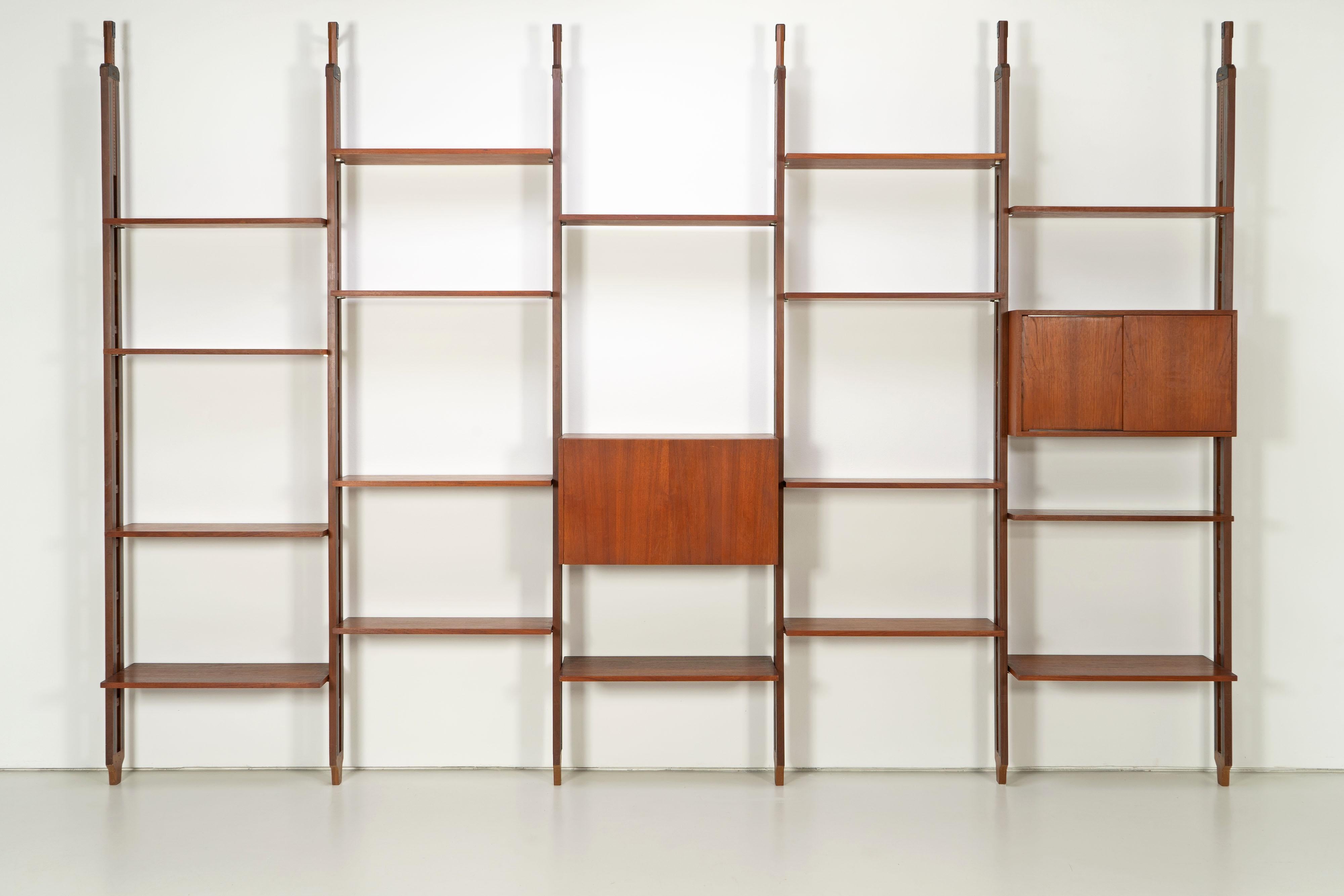 Grande bibliothèque de Paolo Tilche datant des années 1960. L'étagère est fabriquée en teck et se caractérise notamment par une hauteur maximale de 320 cm, la hauteur minimale serait de 275 cm. Des pinces en acier noir sont vissées au sol et au