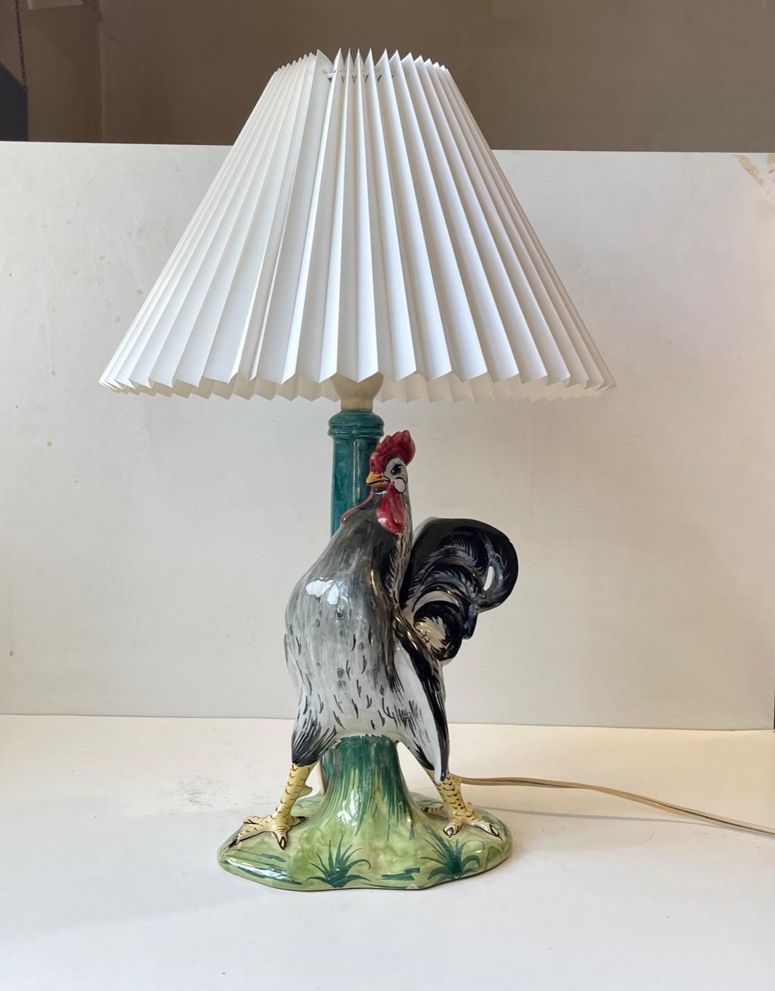 Colorful and 'proud standing' rooster table light fitted with a fluted white shade. The lamp base is made and hand-painted in Italy during the 1950s. It features its original bakelite socket and is in working order. Signed Italy 0182 to its base.