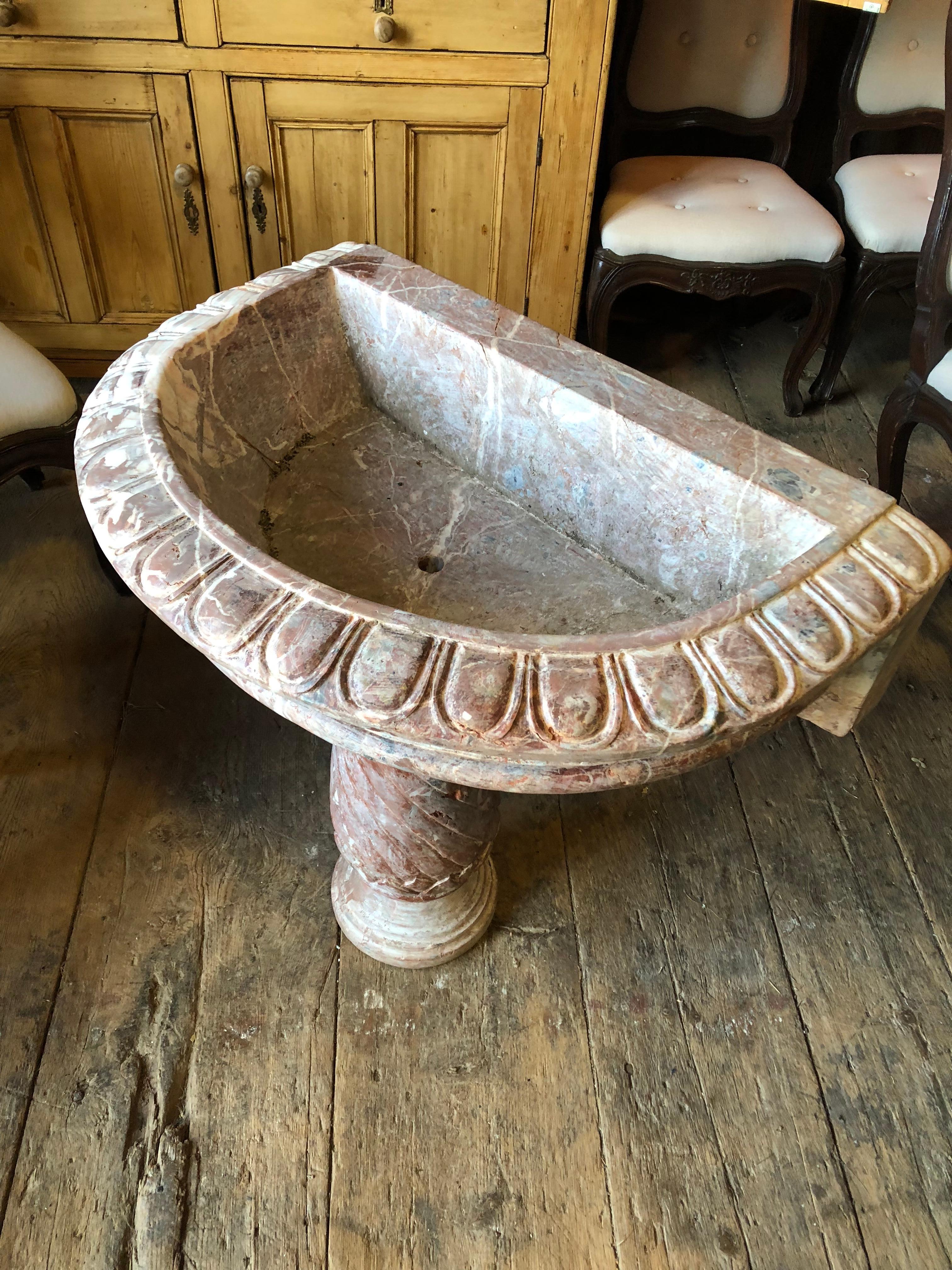 An Italian carved rose marble wall fountain on spiral carved column base, the basin edge carved with egg and dart border, 19th century. Would serve nicely as a sink.
