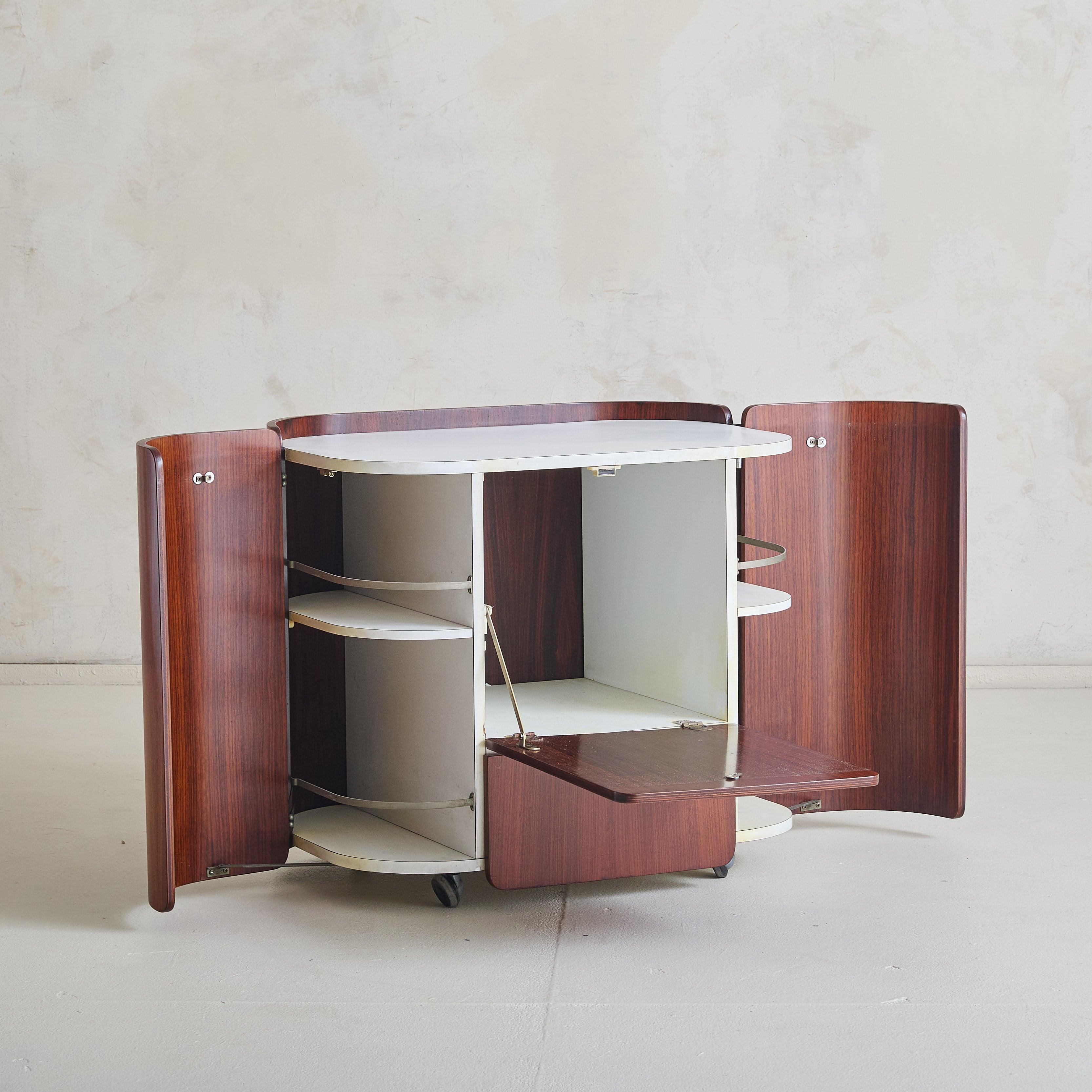 Un mobile bar moderno italiano progettato da Carlo De Carli per Fiarm Scorze negli anni '60. La forma curva è realizzata in ricco legno di palissandro e abbinata a superfici bianche e lisce, creando un contrasto sorprendente. Il bar è dotato di