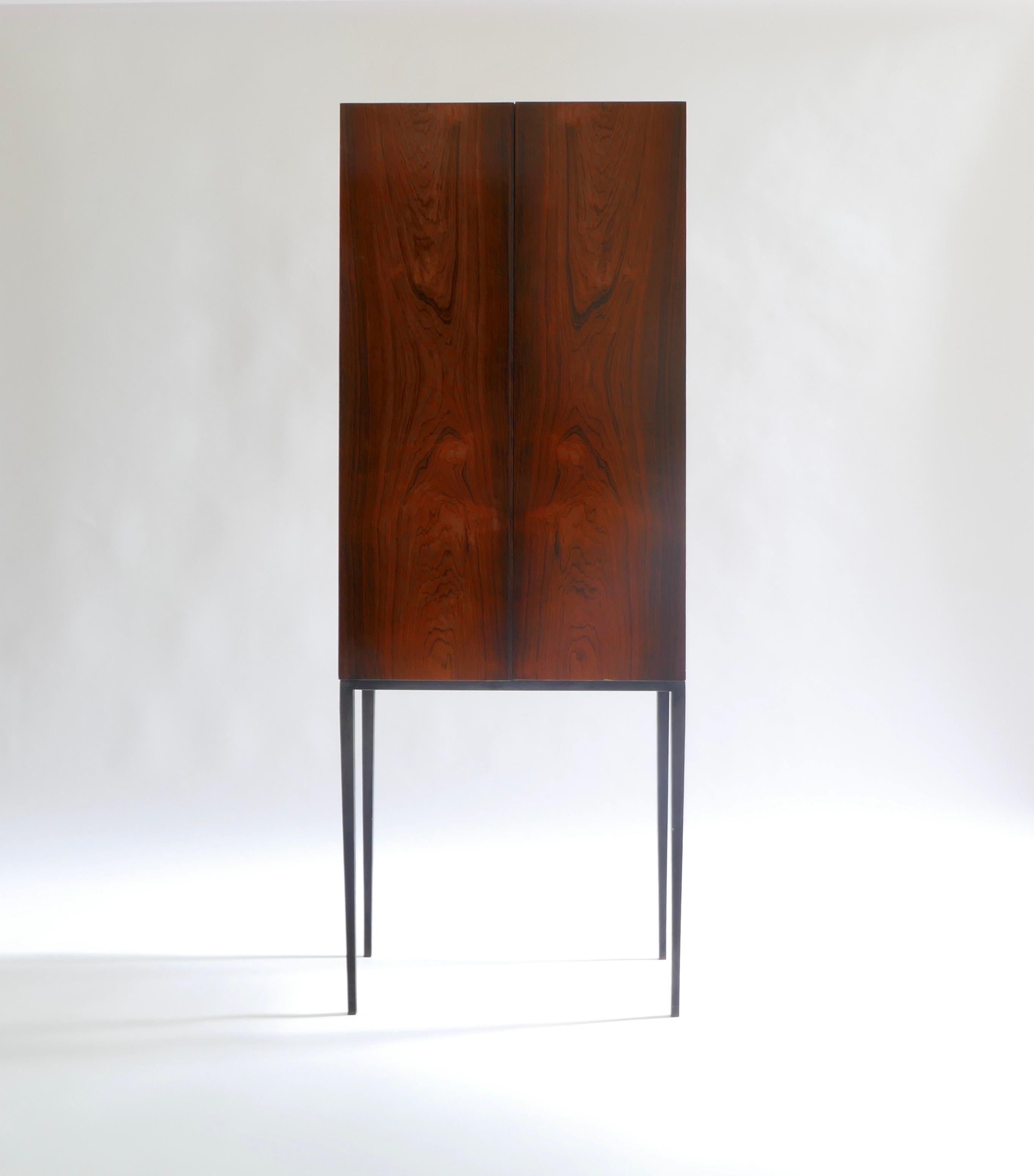 A tall Italian cabinet in rosewood on black iron legs with brass backdrop finishing inside.
One shelf inside for storage in wood whilst the back panel is all in brass.
Very elegant and highly adaptable to store in any room. 

Italy, 1960s.
 