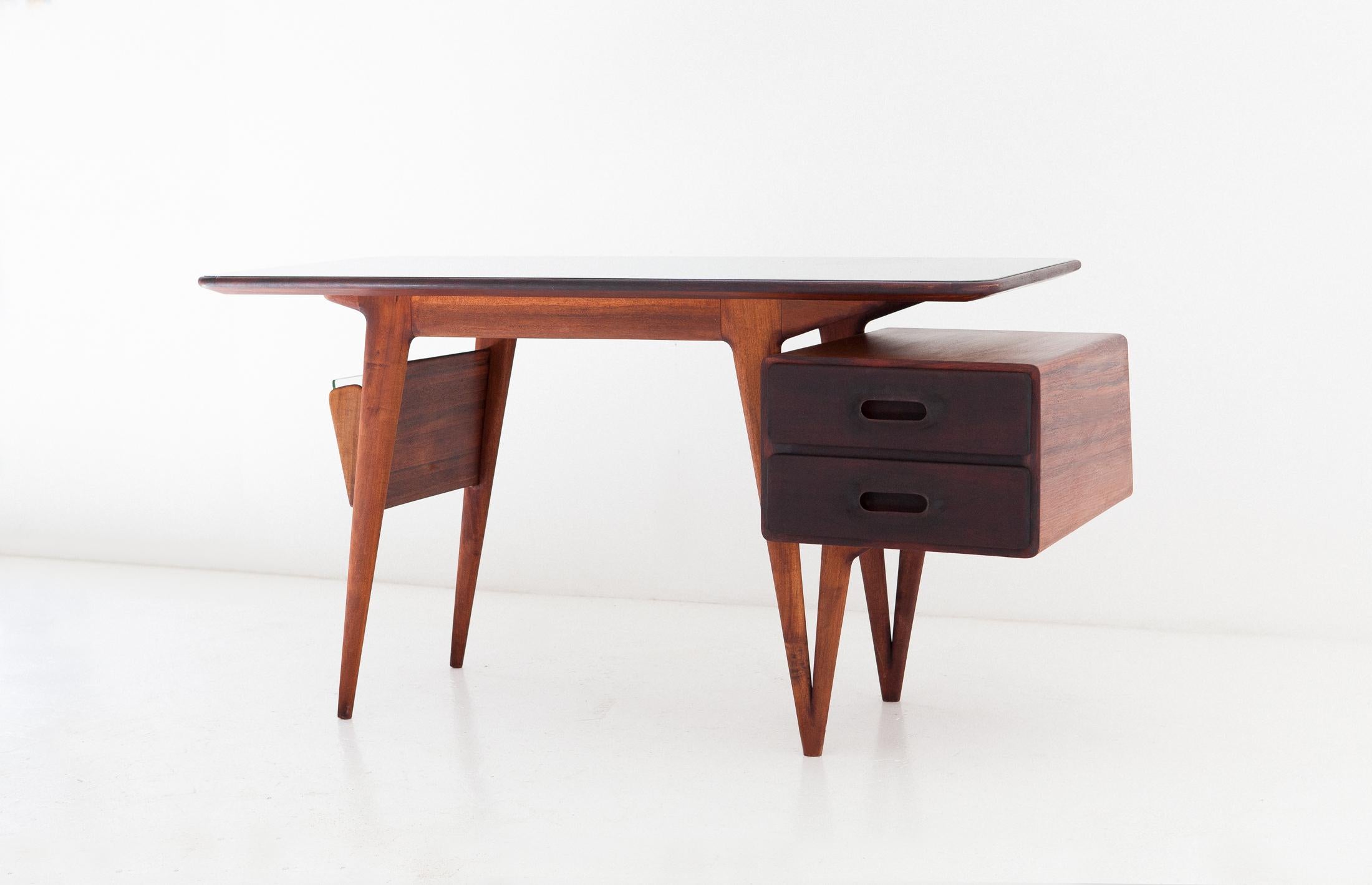 Midcentury desk, manufactured in Italy in the 1950s,

This table feature a green retro-lacquered glass plane, rosewood frame.
The ultra modern but soft lines, the lightness of the design, the incredible handwork of the drawer handles make this