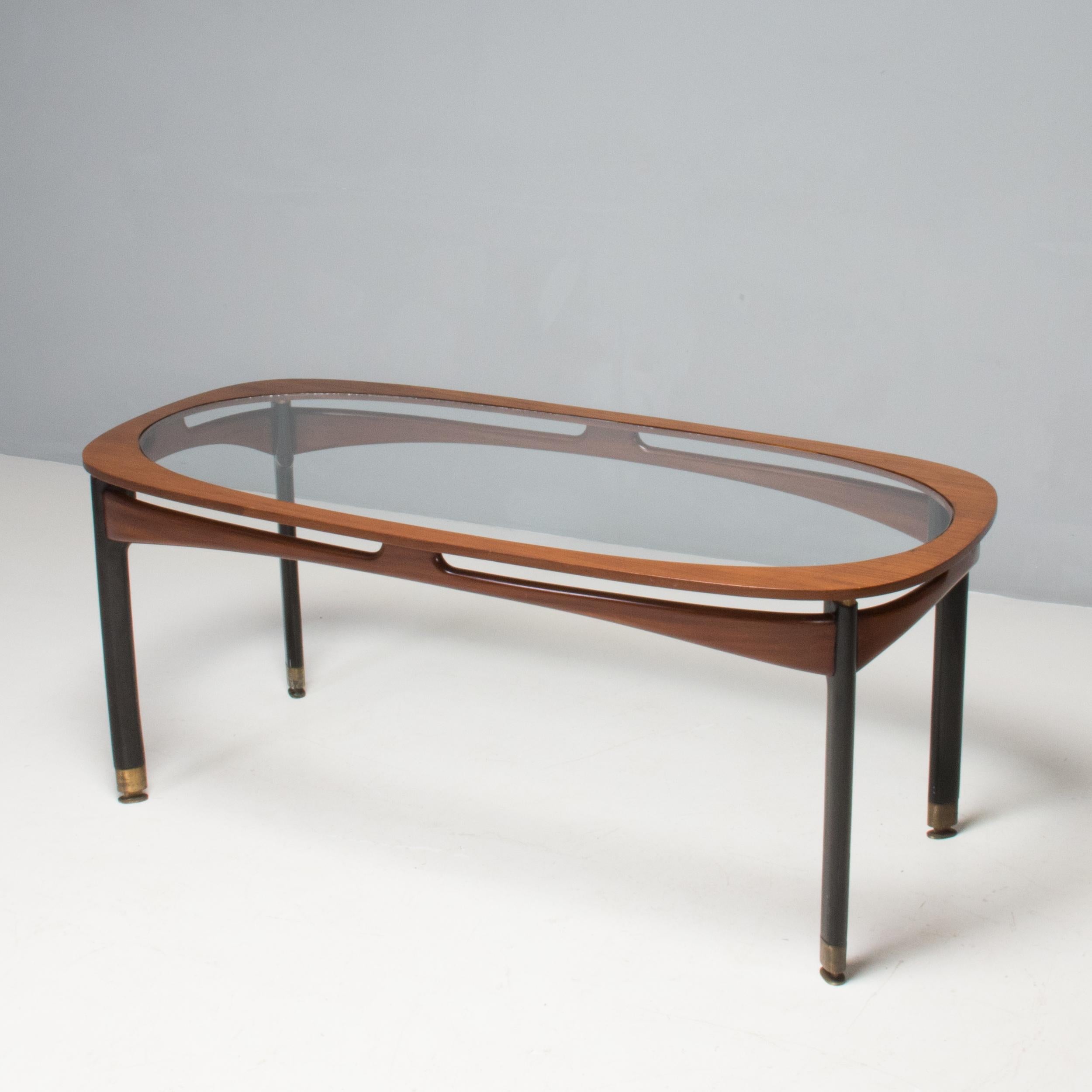 A stunning example of mid-century Italian design, this dining table is from the 1950s.

Constructed from a rosewood frame, the table has black lacquered legs with brass sabots and detailing. 

The rectangular tabletop has curved-off corners and