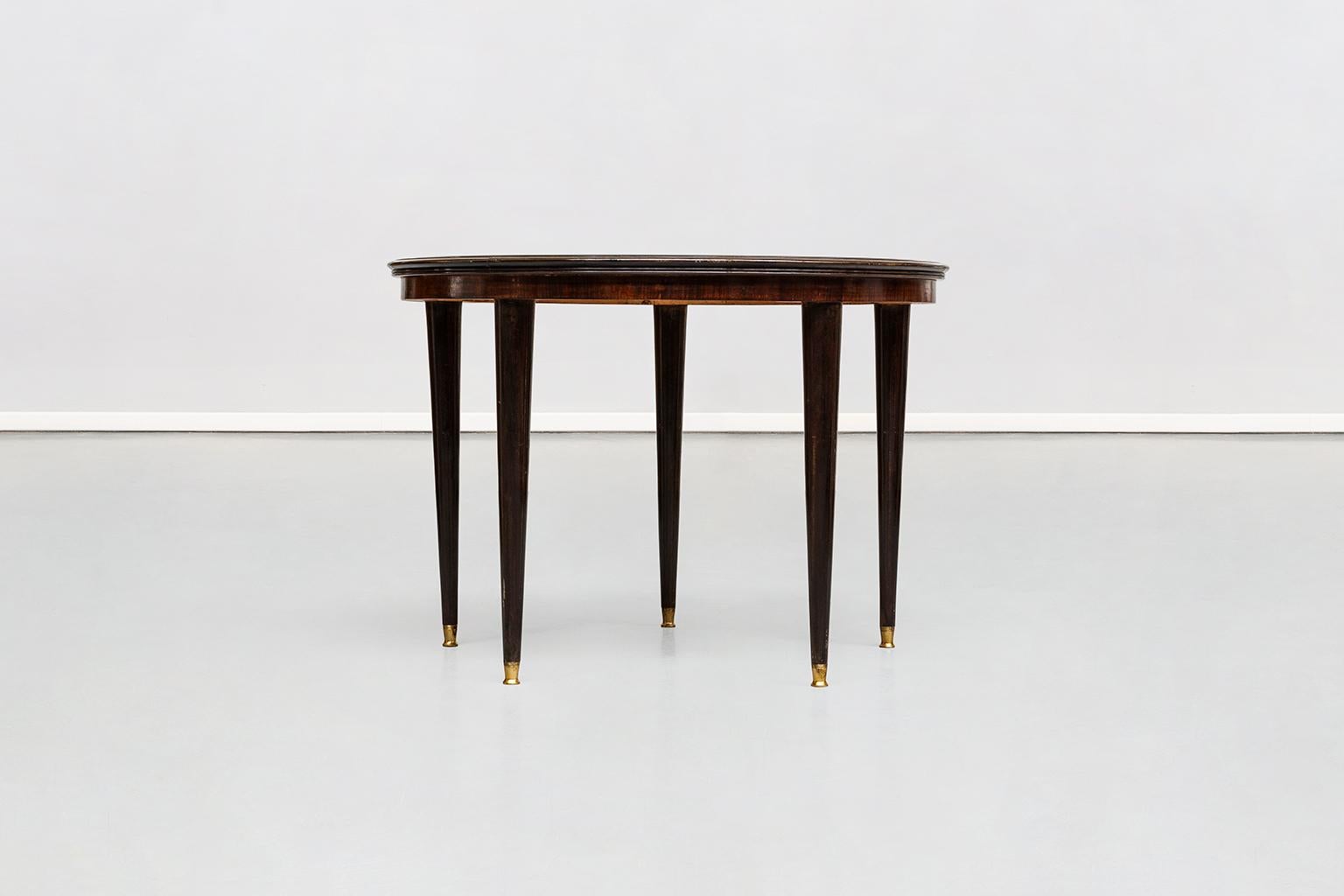 Italian rosewood round five legs dining table in the style of Dassi, 1950s
Italian rosewood dining table in the style of Dassi on high conical legs with brass details and round tabletop with original glass top. Absolutely uncommon the presence of