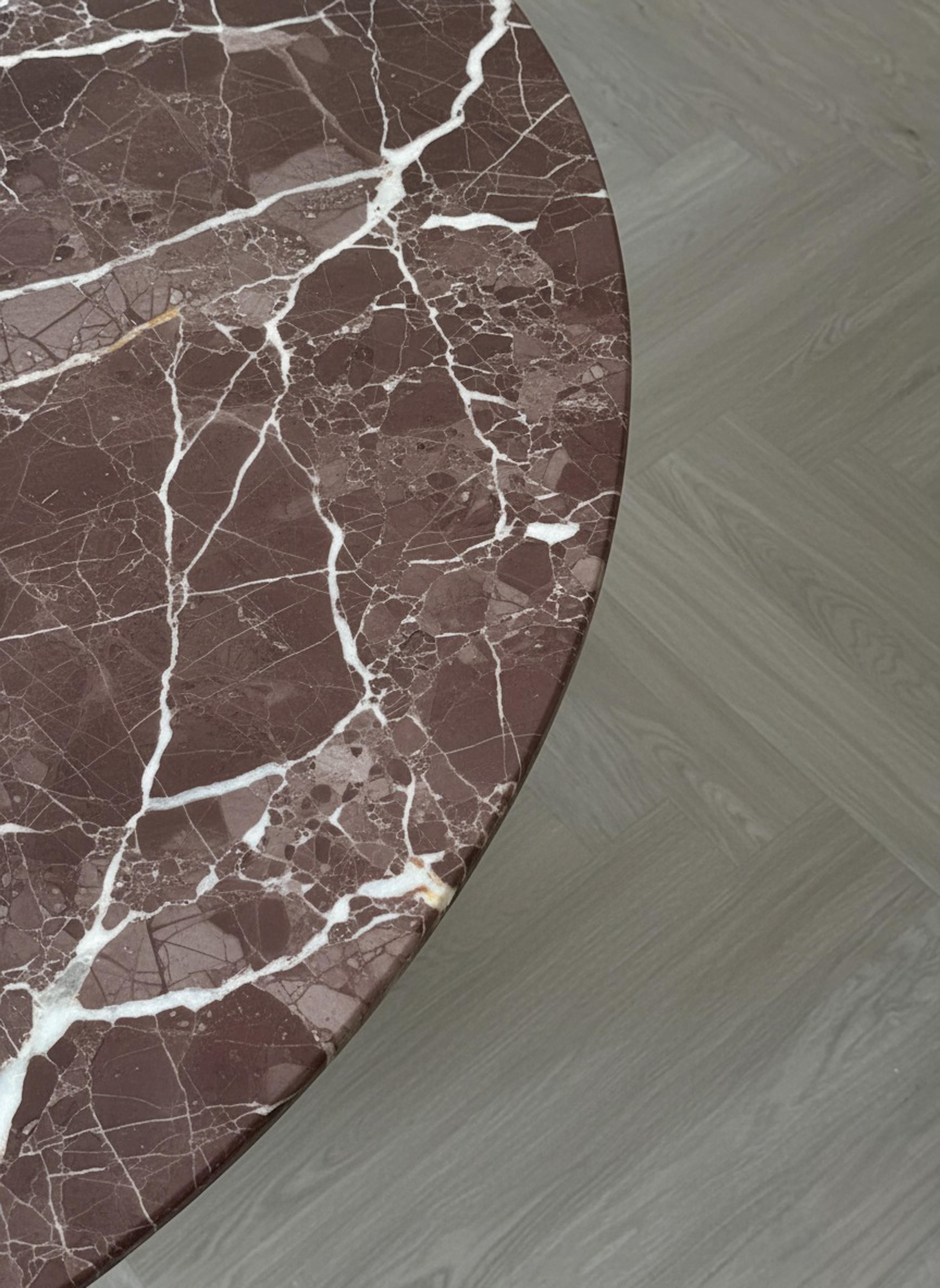 Elaborada íntegramente con el magnífico mármol Rosso Levanto, esta mesa de comedor totalmente redonda es una expresión atemporal de la elegancia y la artesanía italianas. Los ricos tonos burdeos, realzados por un llamativo veteado blanco, crean una