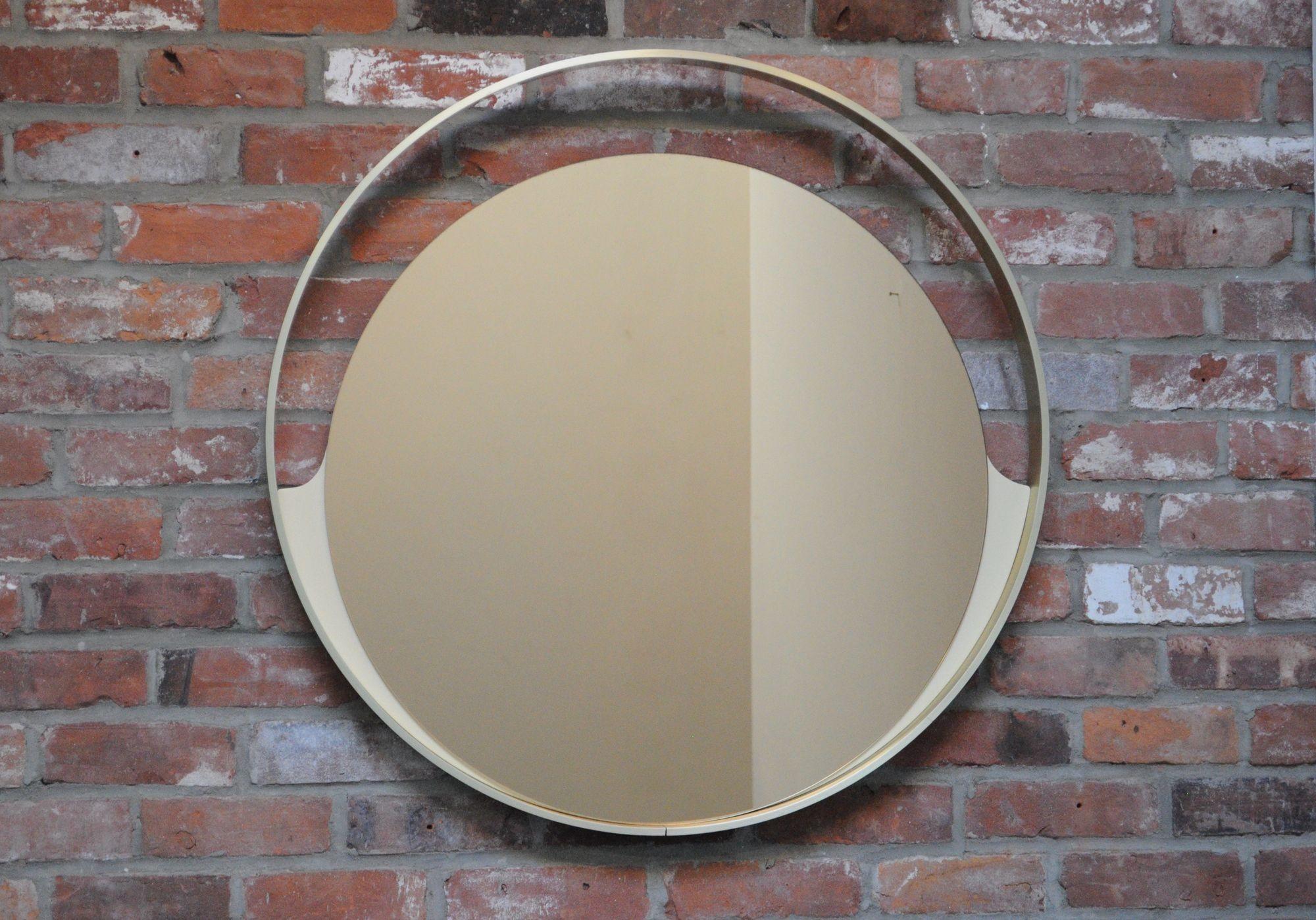 Rimadesio wall mirror composed of a gold anodized aluminum 'ring' frame with cream/ivory lacquered wood accents supporting a bronze-tinted mercury mirror glass plate (Desio, Italy, ca. 1960s).
Extremely well made incorporating quality materials