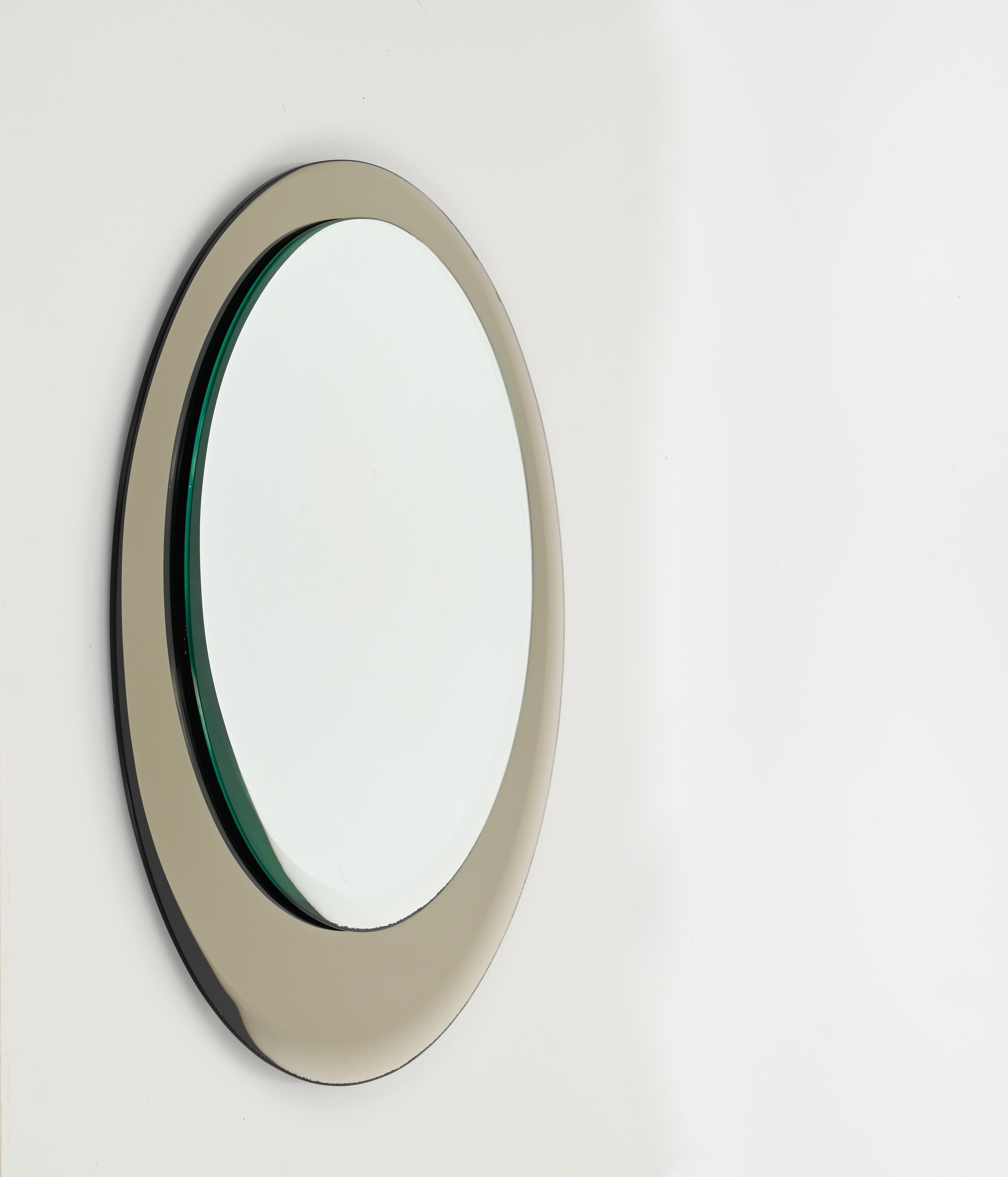 Merveilleux miroir rond double biseauté du milieu du siècle avec un superbe cadre en verre bronzé. Ce fantastique miroir a été fabriqué en Italie dans les années 1970 par Cristal Arte.

Ce miroir est magnifique car il a un design élégant avec un
