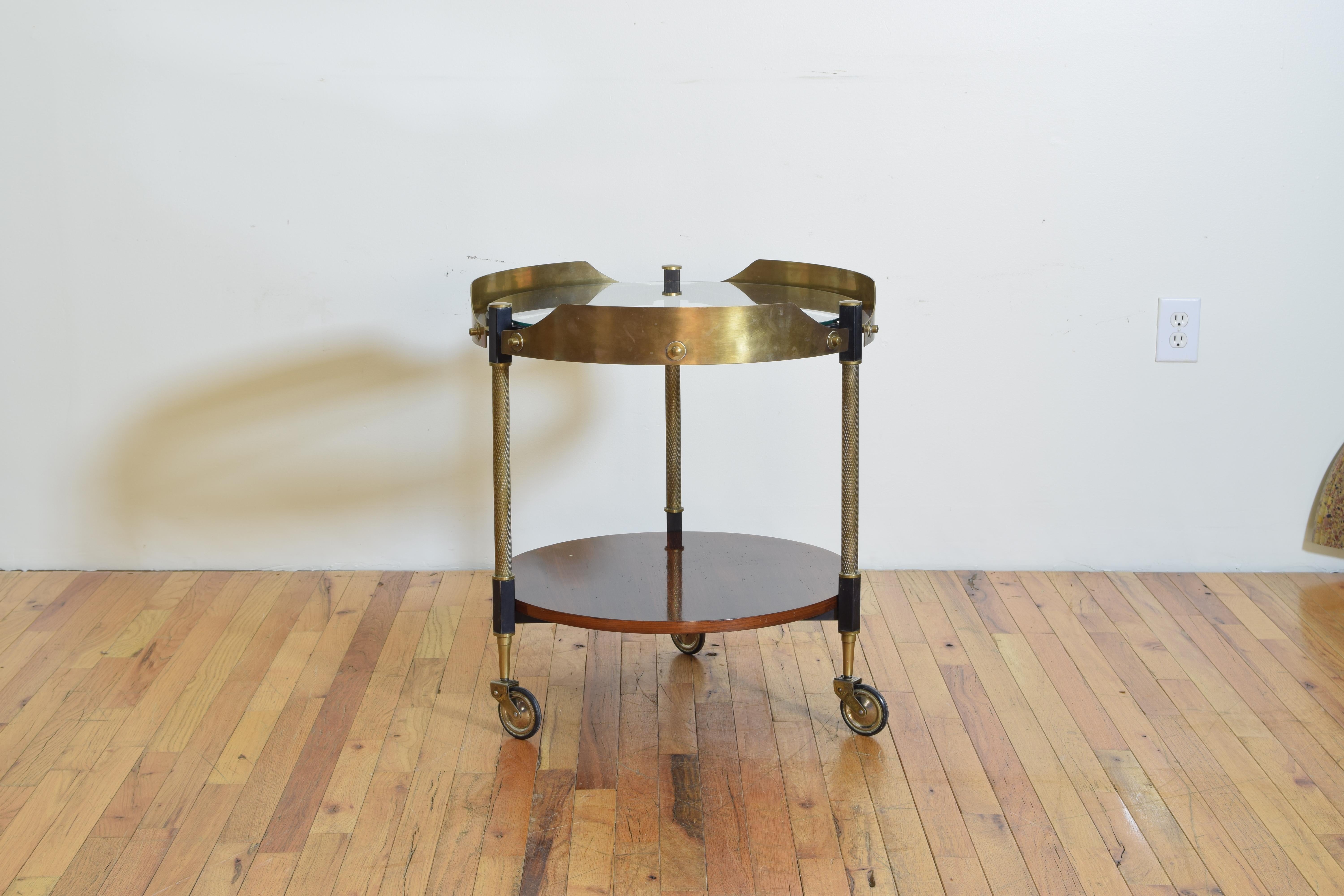 Having a raised brass gallery and a glass top, the bottom tier veneered in Macassar rosewood, resting on original brass and rubber wheels.