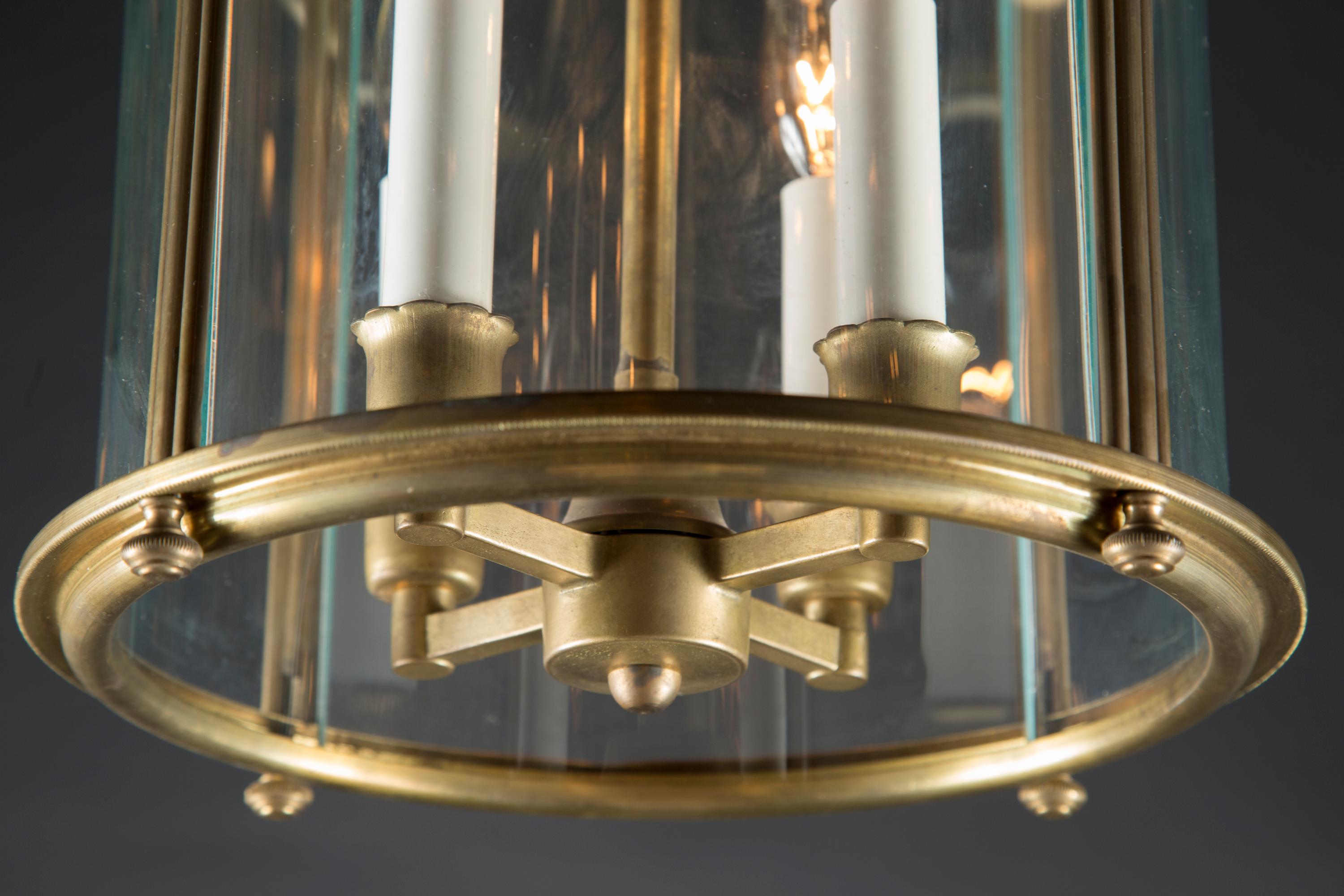 This beautiful pair of brass lantern features a curved glass pane and is adorned with patterned finials at all four corners of the fixture's bottom. The vintage Italian piece dates back to the mid 20th Century and sports a beautiful uniquely shaped