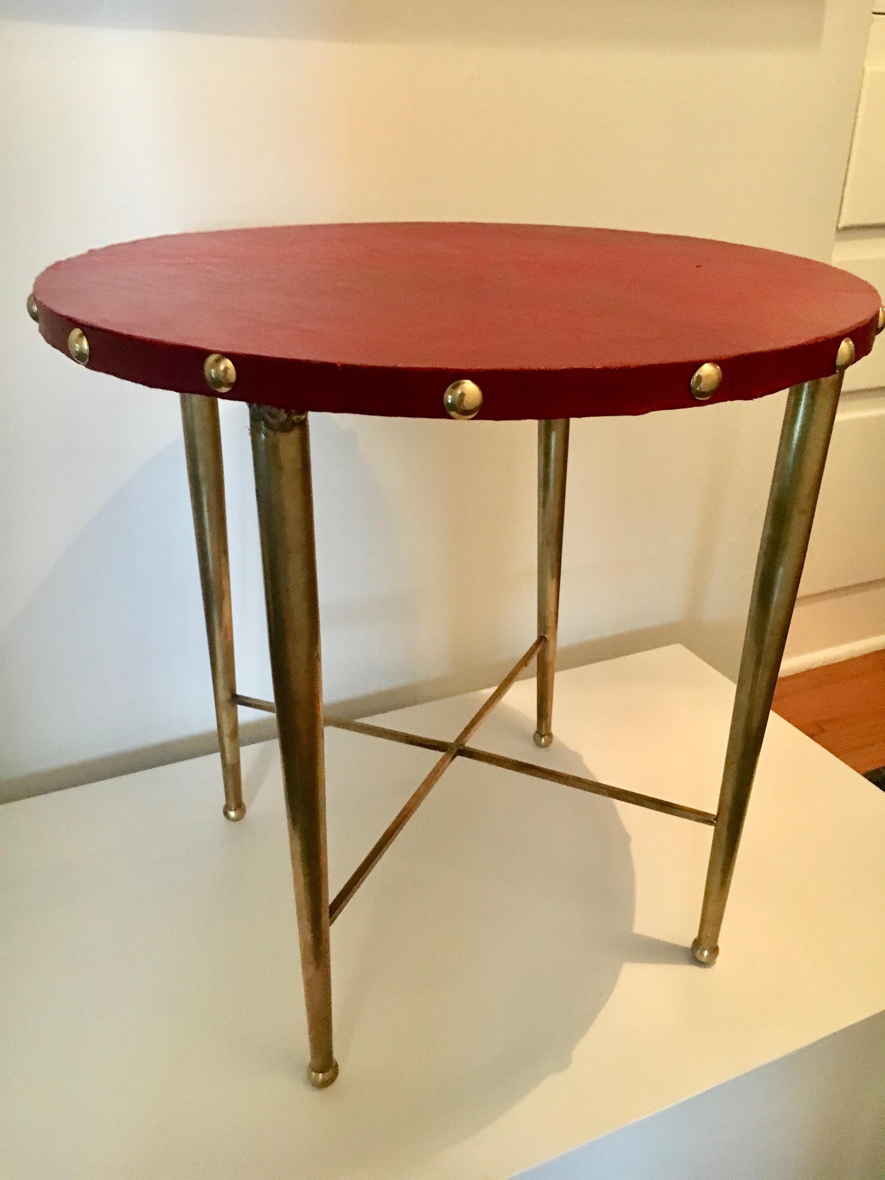 Italian round brass table with leather top after Gio Ponti, a side or martini table with red leather top and brass studs and brass legs, many qualities and inspiration of Ponti.