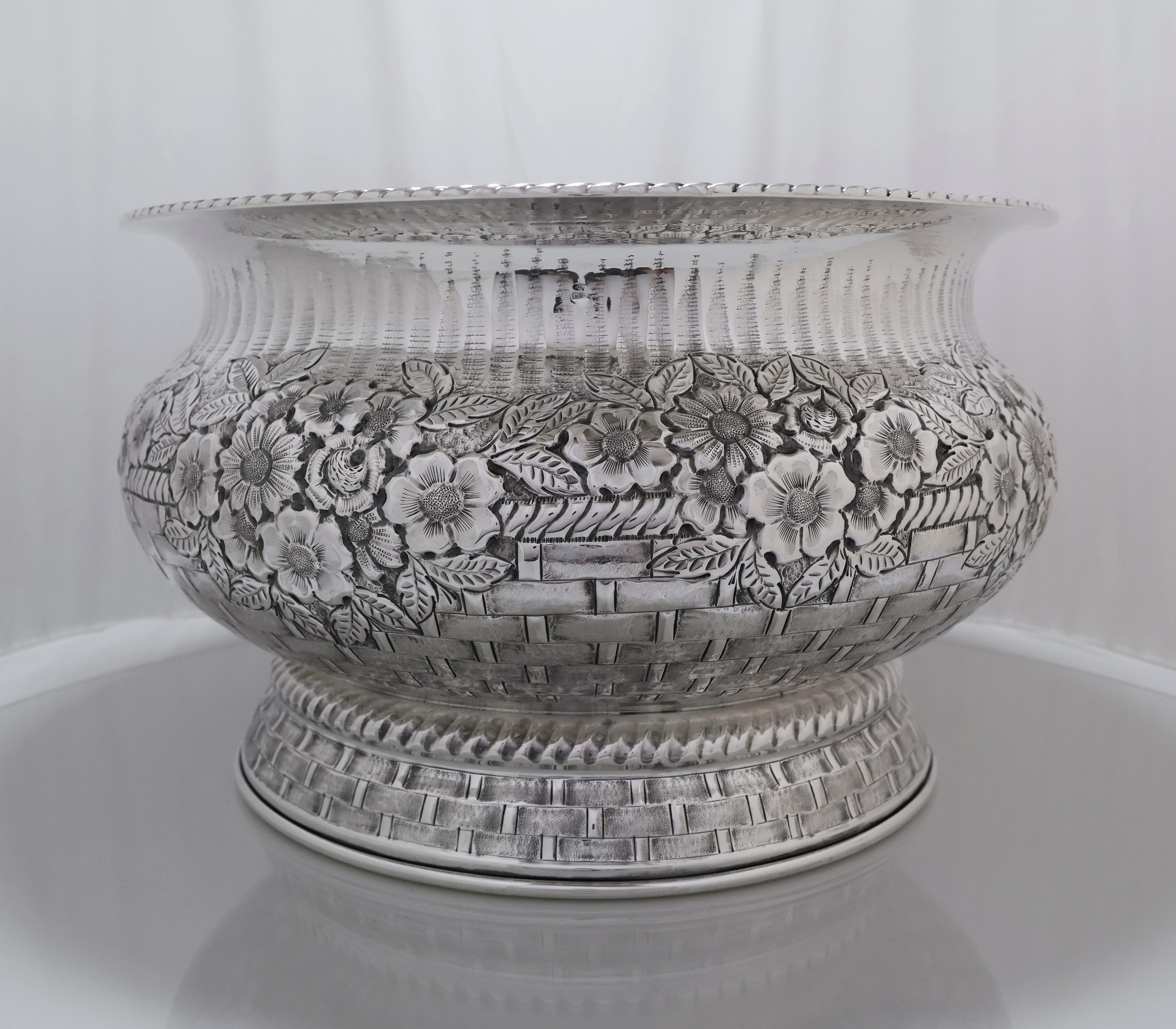 Elegant round centerpiece bowl crafted in 800 silver by the artisan Fani, Italy, dated 1900. The piece features an ornate corded border and intricate repoussé floral designs that encircle the body, combined with a detailed woven basket motif on the