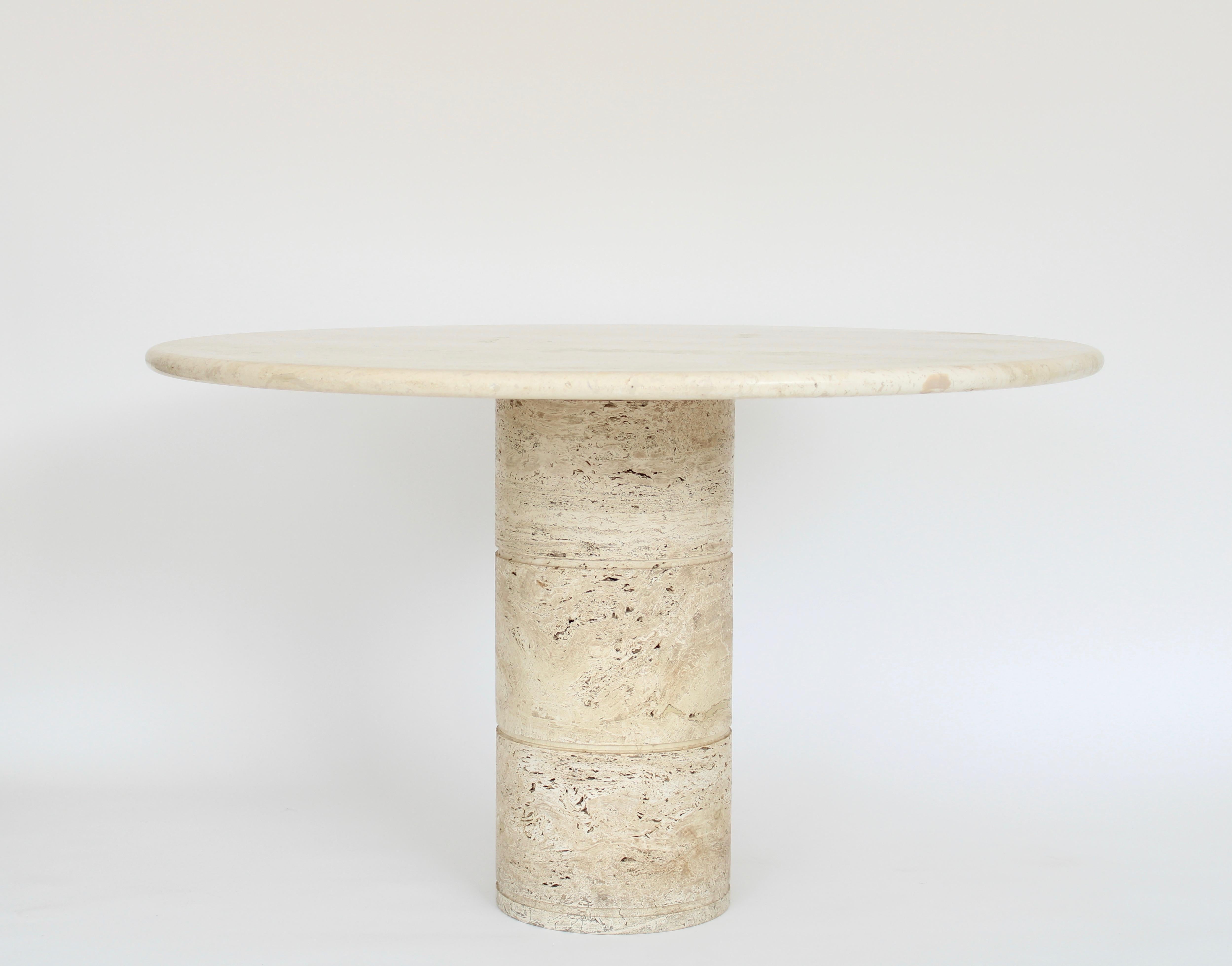 Italian round top cream travertine dining or center table on a round column base.
Variegated tones of cream and beige travertine marble, Italy, circa 1970.
The top is honed and not shiny but sealed with a matte sealer.
The base is more heavily