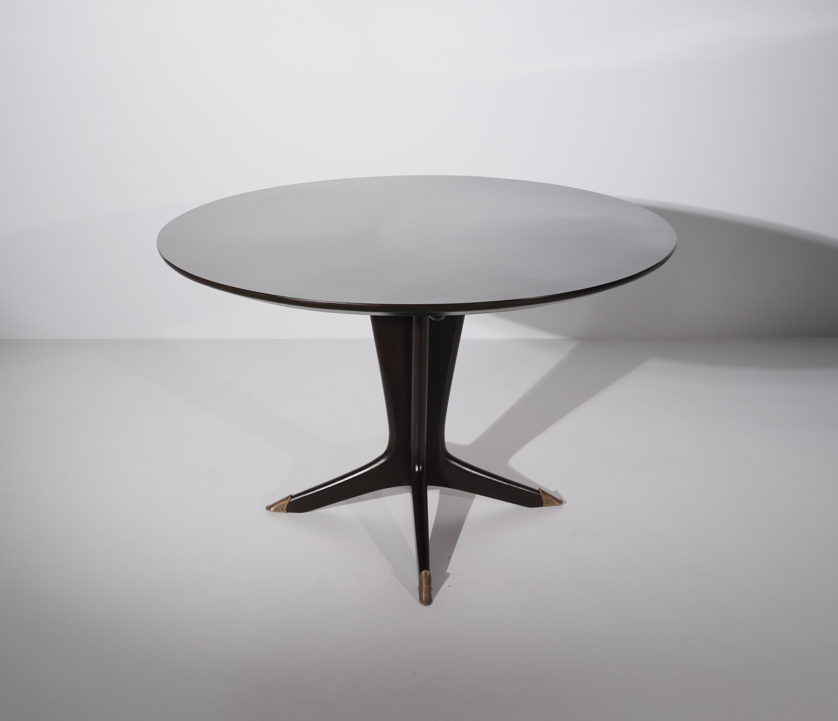 A dining table, manufactured in Italy during the 1950s   

Round Table in dark brown lacquered  wood , fully restored
High Italian carpentry, elegant and sculptural modern design.