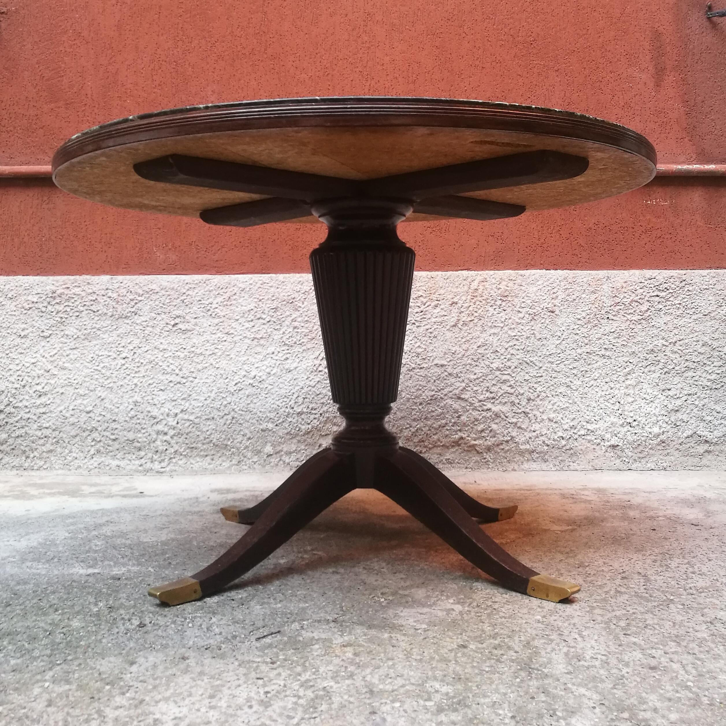 Italian round dining table with green marble, 1950s
Round dining table made in Italy from fifties. A wooden four-legs structure, with brass tips and a central turned column, where is placed a marble top encased in a decorative frame. This is a