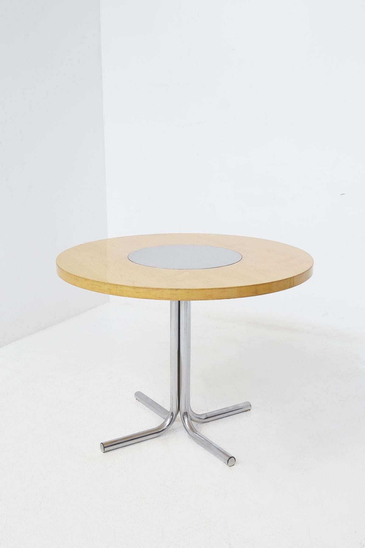 Italian round table of Elam production by Gae Aulenti attr. from the 1970s. The table has a chromed steel pedestal frame. Its pedestal is formed by 4 steel tubes that both radiate on the floor. 
The table top is round in an excellent light wood, at