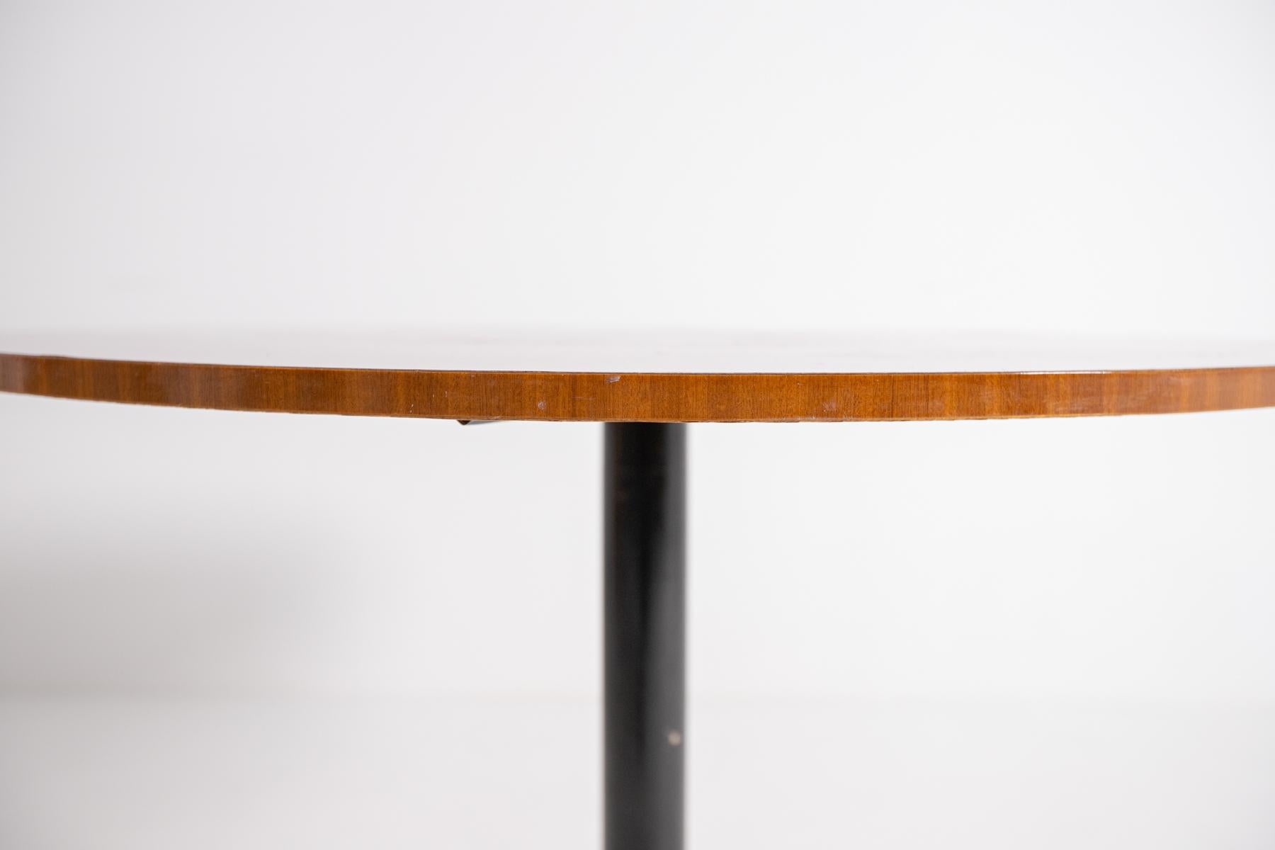 Italian modernist round table from the 1950s.
The table features a round top totally made of wood. Its structure is made of black painted iron. The table is supported by a single iron pedestal and at the base its four legs radiate around its entire