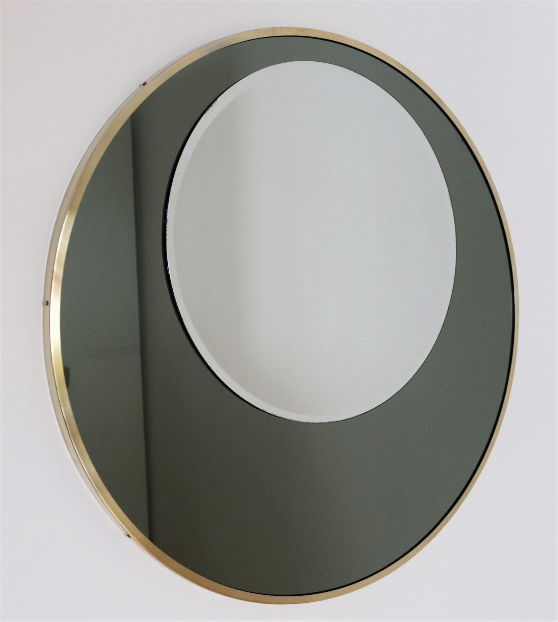 Gorgeous wall or console mirror with two round superimposed mirror glasses and brass frame.
The mirror is made in Italy during the 1970s.
The lower bigger mirror is made of olive green color, the upper smaller mirror is normal not colored mirror