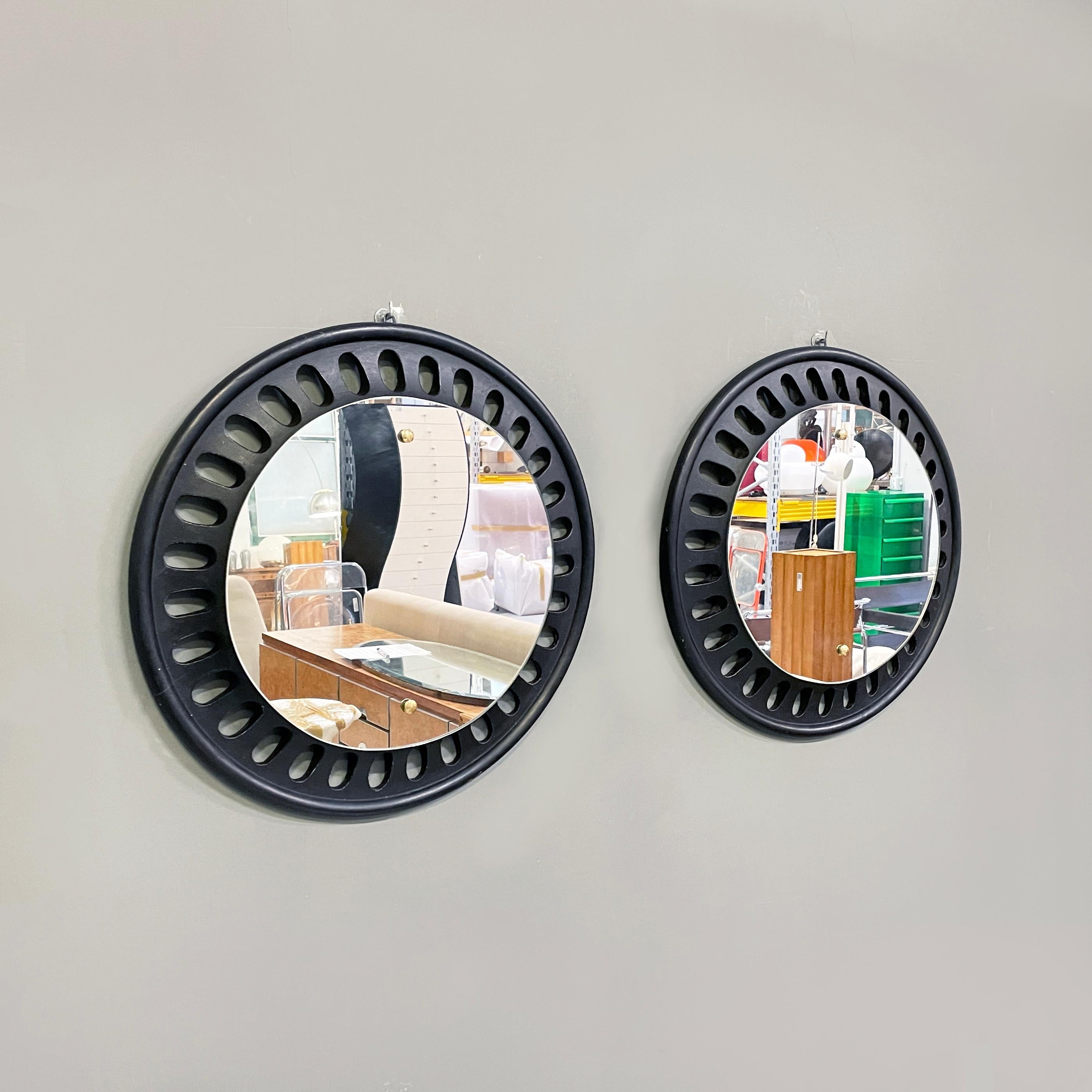 Italian Round wall mirrors in black wood, 20th century
Pair of round wall mirrors in black painted wood. The frame has oval decorations. Small brass buttons on the mirror. 
20th century.
Good condition, light marks on the wood. The brass is in