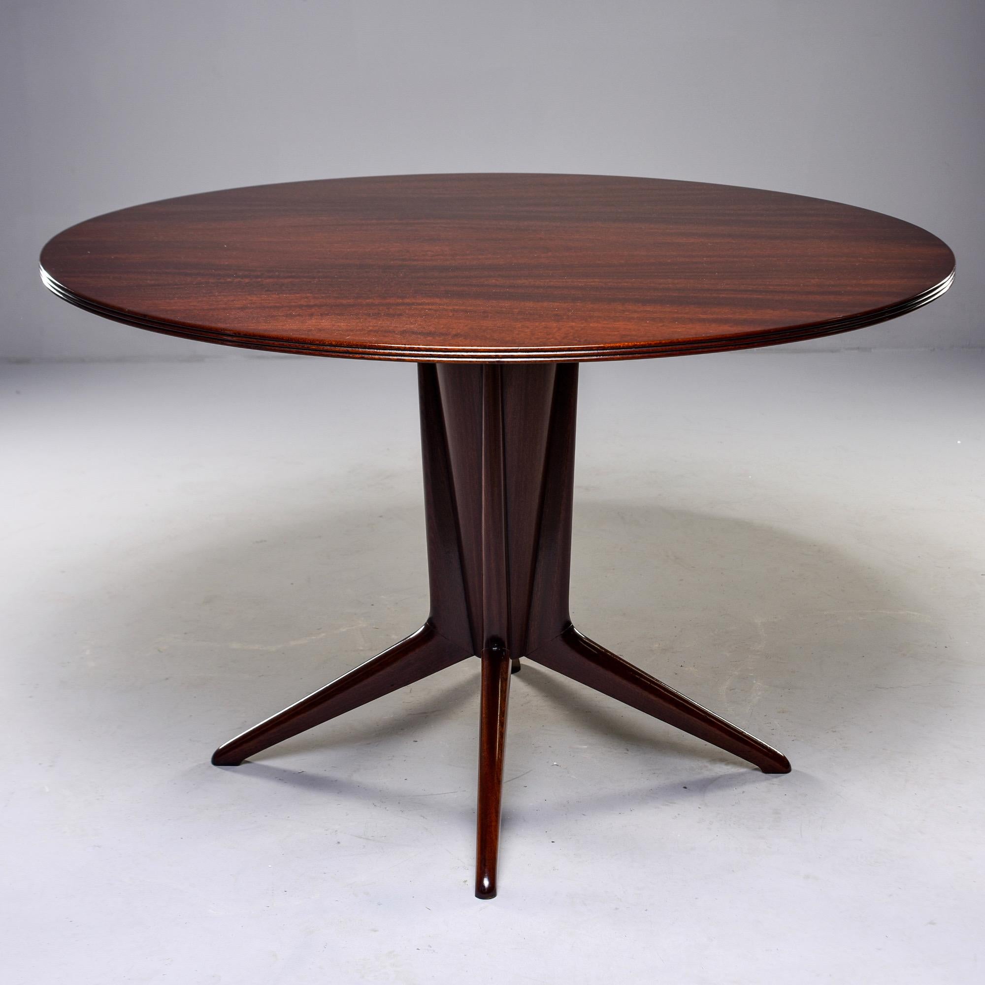Italian walnut table with versatile 48” round top, circa 1960s. Sculptural four-footed pedestal base. Unknown maker.