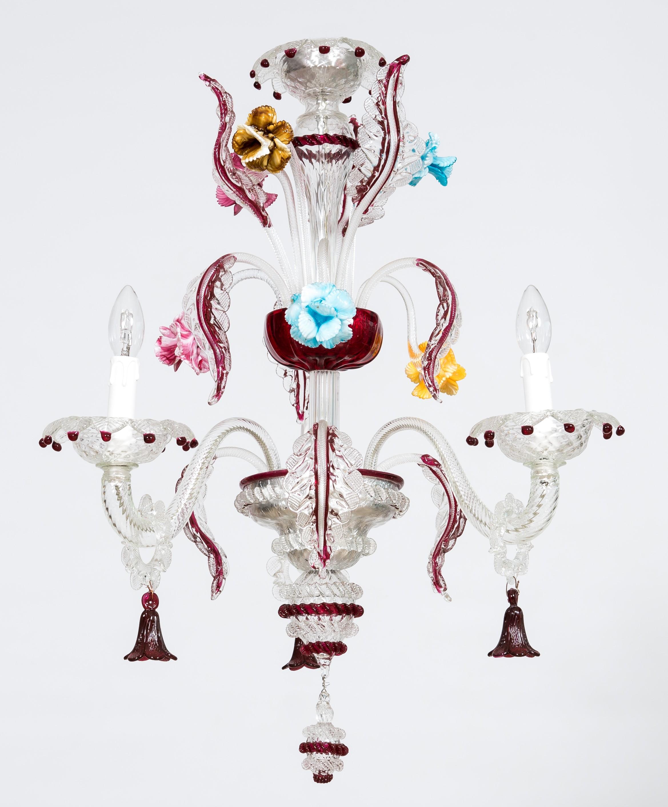 Italian ruby red glass paste chandelier in Murano, 1990s Giovanni Dalla Fina.
Three wavy arms and three downwards-leaning leaves arise from the lowest cup. Each arm holds a light at its outer extremity, and is embellished by a transparent ring