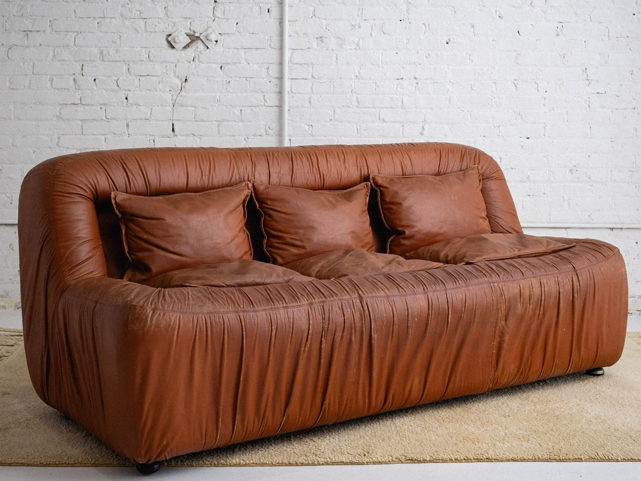 A space age Italian leather sofa in the style or De Pas, D'Urbino, Lomazzi. Rushed camel leather. Three removable upper cushions. Two chairs and one sofa available, sold separately. Sourced in Northern Italy. 