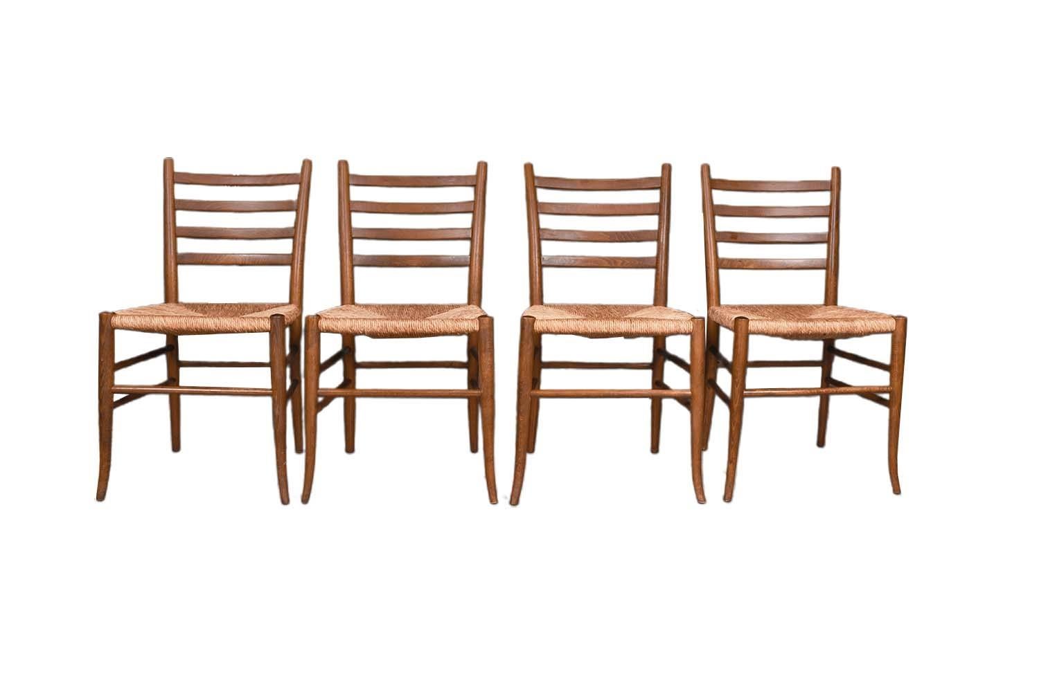 Four beautifully grained walnut Italian ladder back dining side chairs with original rush seats, in the style of Gio Ponti, stamped Made in Italy circa 1960s. Each chair features four tight horizontal ladder back rails, modernist subtle curved sabre