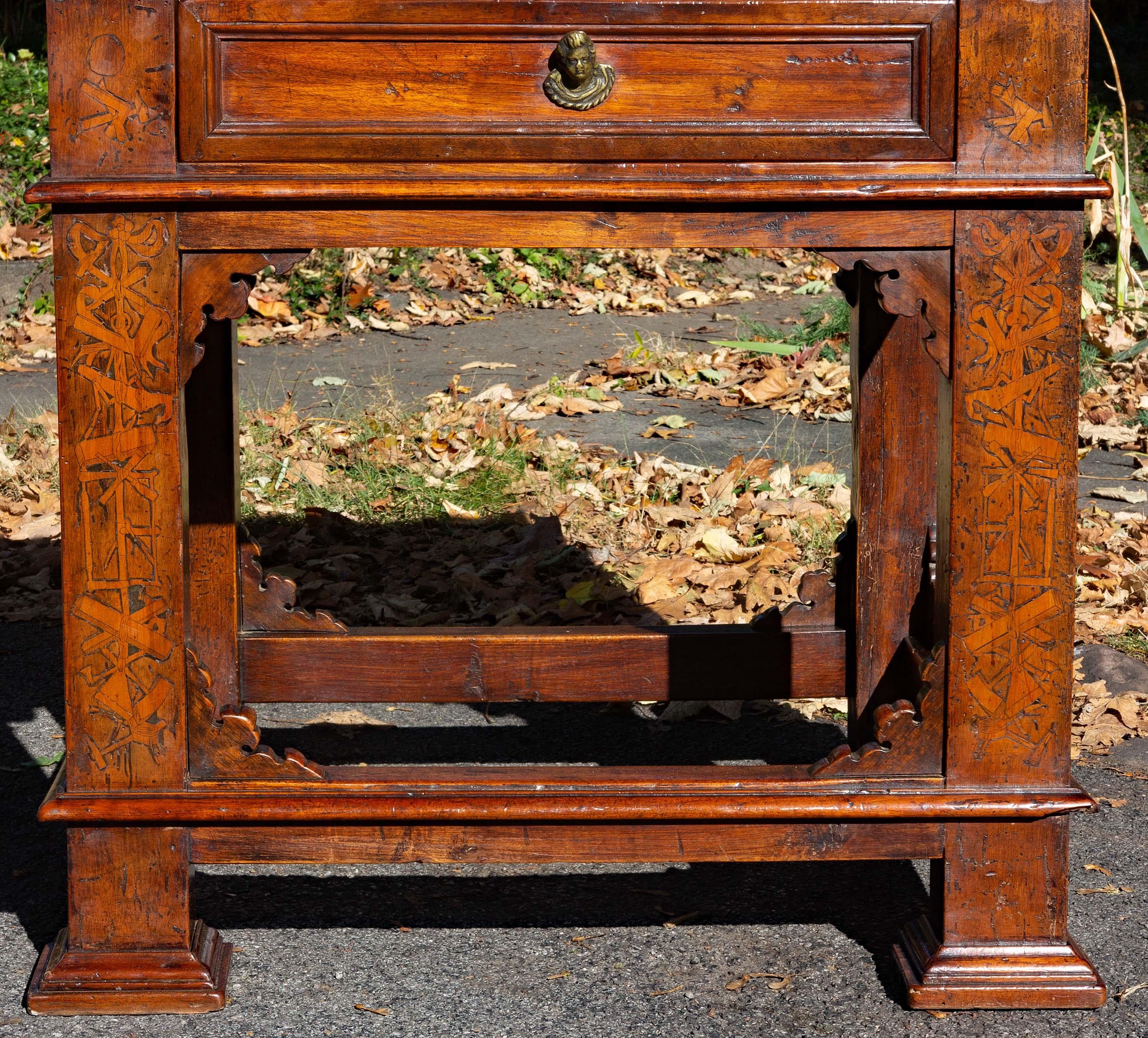 A substantial rustic Italian baroque one drawer table with marquetry. Solid walnut with very unusual marquetry. The table is decorated on all four sides and may be used as a center or library table. The inlay shows all the many tools of a furniture