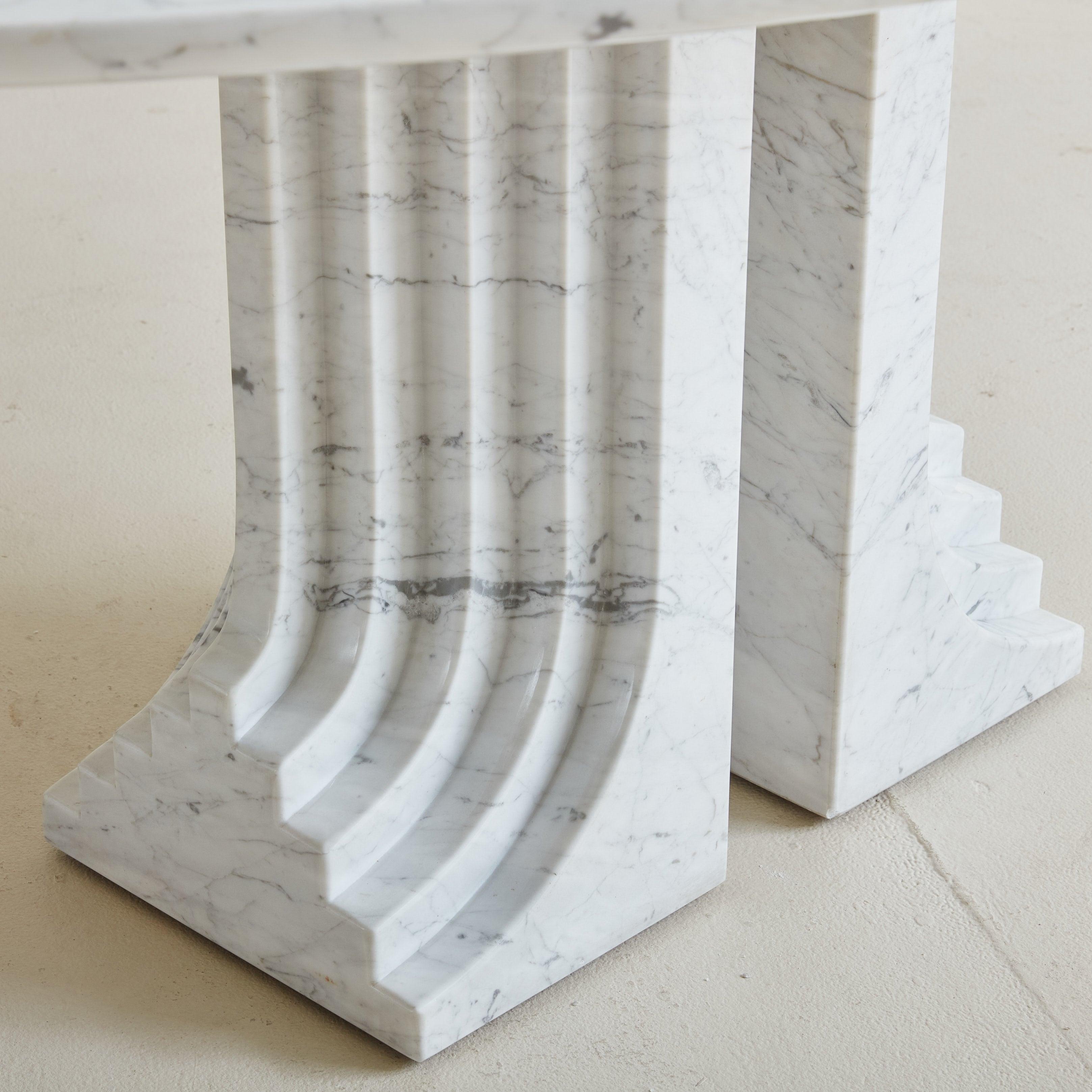 Carlo Scarpa's ‘Samo’ dining table was designed for Simon Gavina in 1971. Part of the 'Ultrarazionale' collection, this rare piece features two grooved Carrara marble pillars supporting a floating oval marble top. The pillared base mirrors the