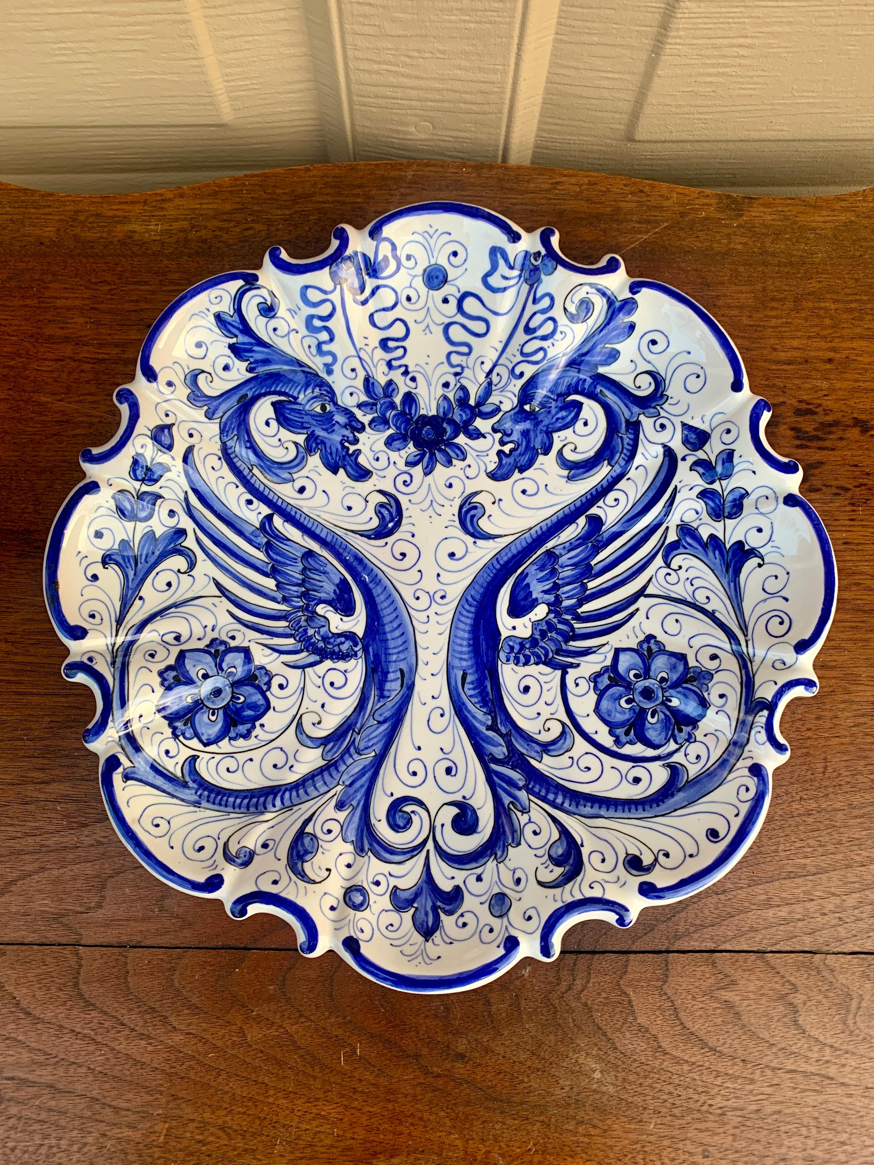 A beautiful French Provincial style hand painted blue and white faience pottery wall plate featuring stylized Allegorical dragons and floral designs.

By Santucci for Deruta

Italy, Late-20th Century

Measures: 10.75