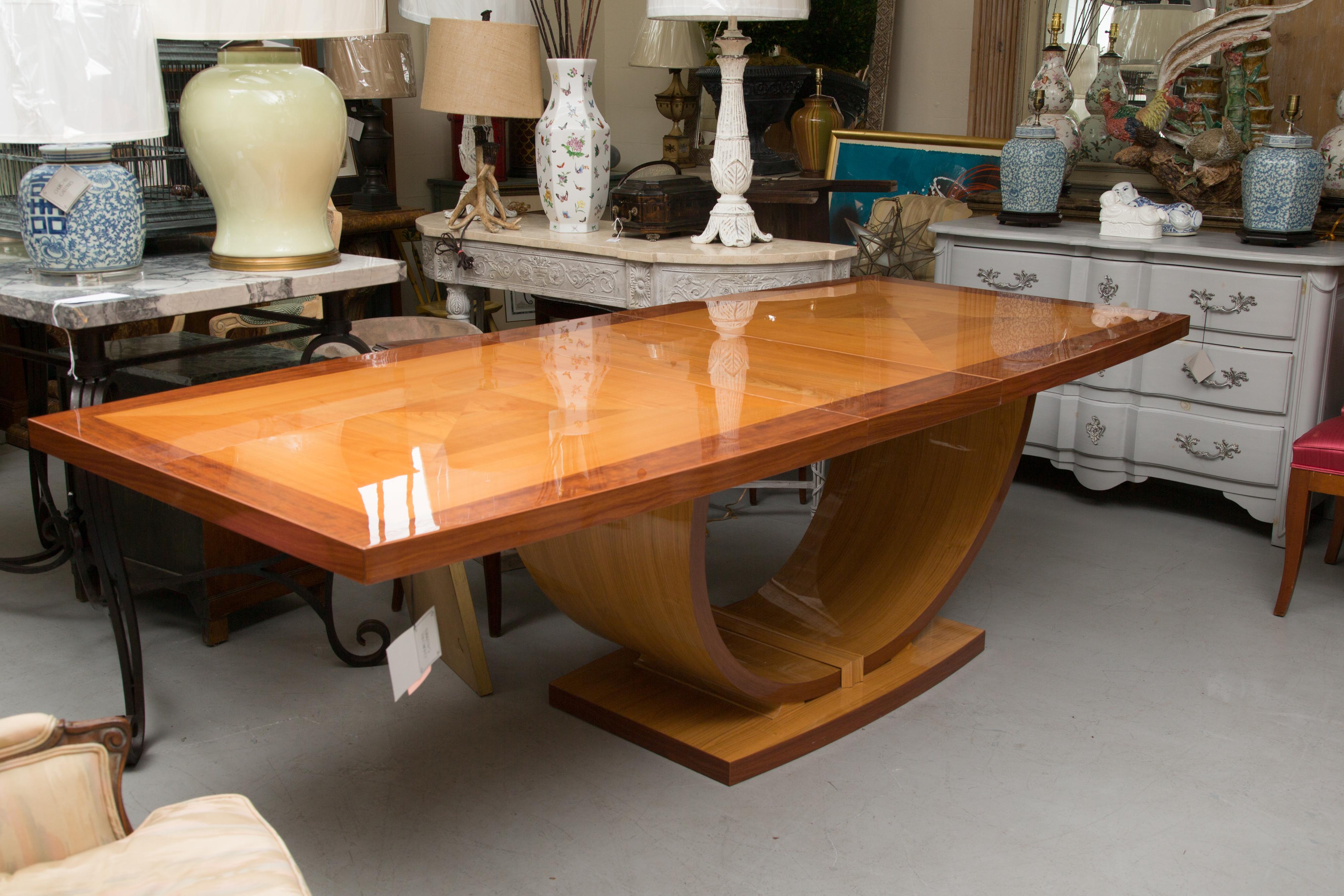 This highly polished Italian handmade table is in rectangular form. The top is supported by a base with arches and is joined by a conforming rectangular base. The top is banded and has a geometric diamond inlaid form flanked by triangles. The table