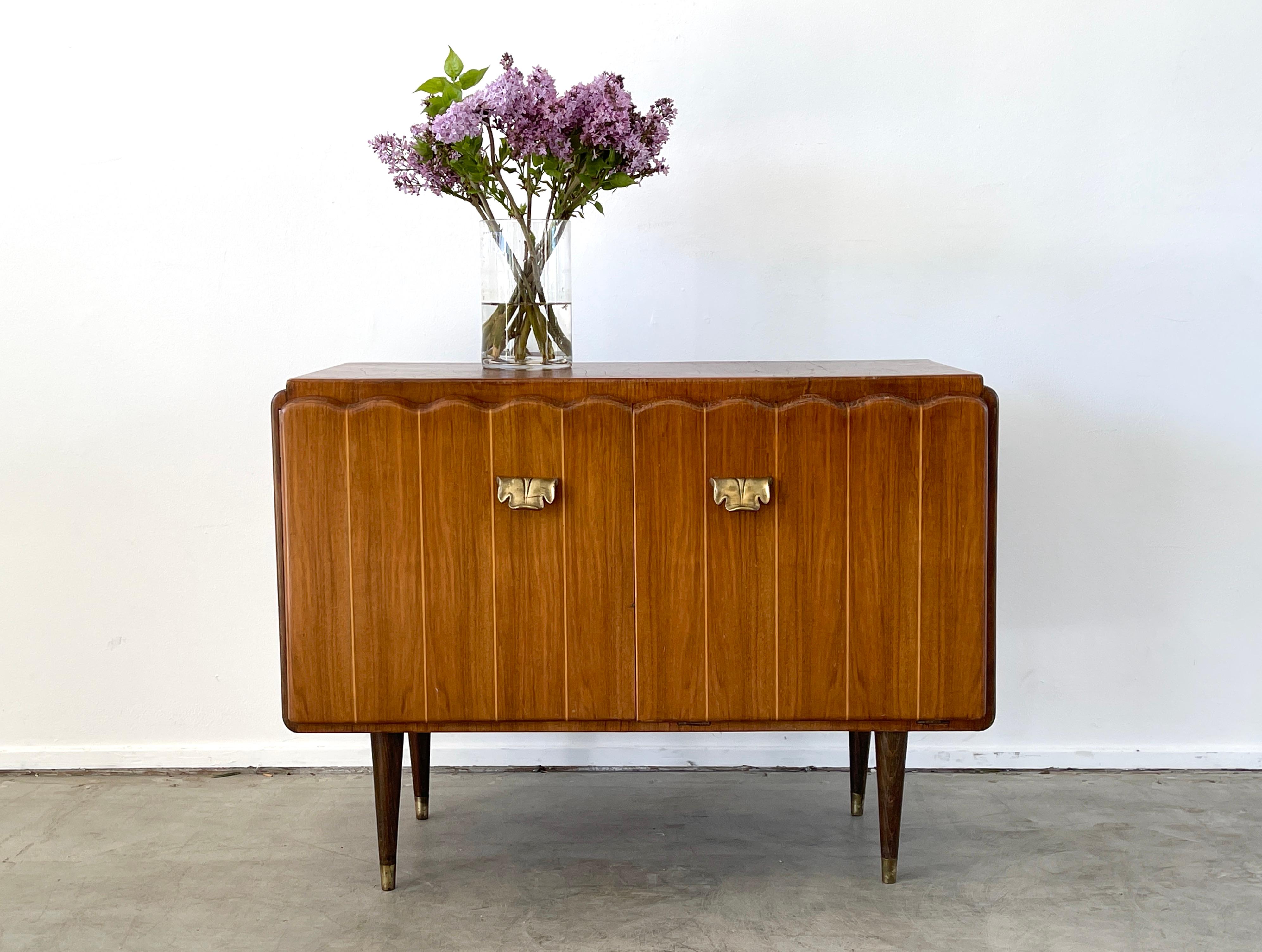 Unique 1950's Italian bar cabinet with scalloped door fronts in boxwood and ornate brass hardware.
Left door opens to reveal mirrored interior with shelf and brass glass holder on back of door. 
Right door pivots open to hold glasses. 
Walnut